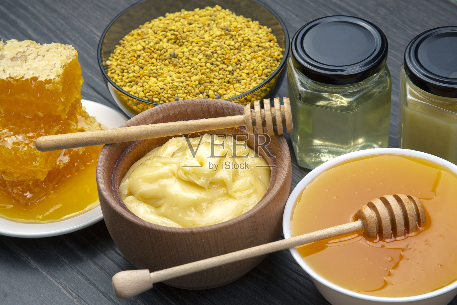 不同品种的新鲜花蜜,花粉和蜂窝与勺子在木制背景。有机维生素保健食品照片摄影图片
