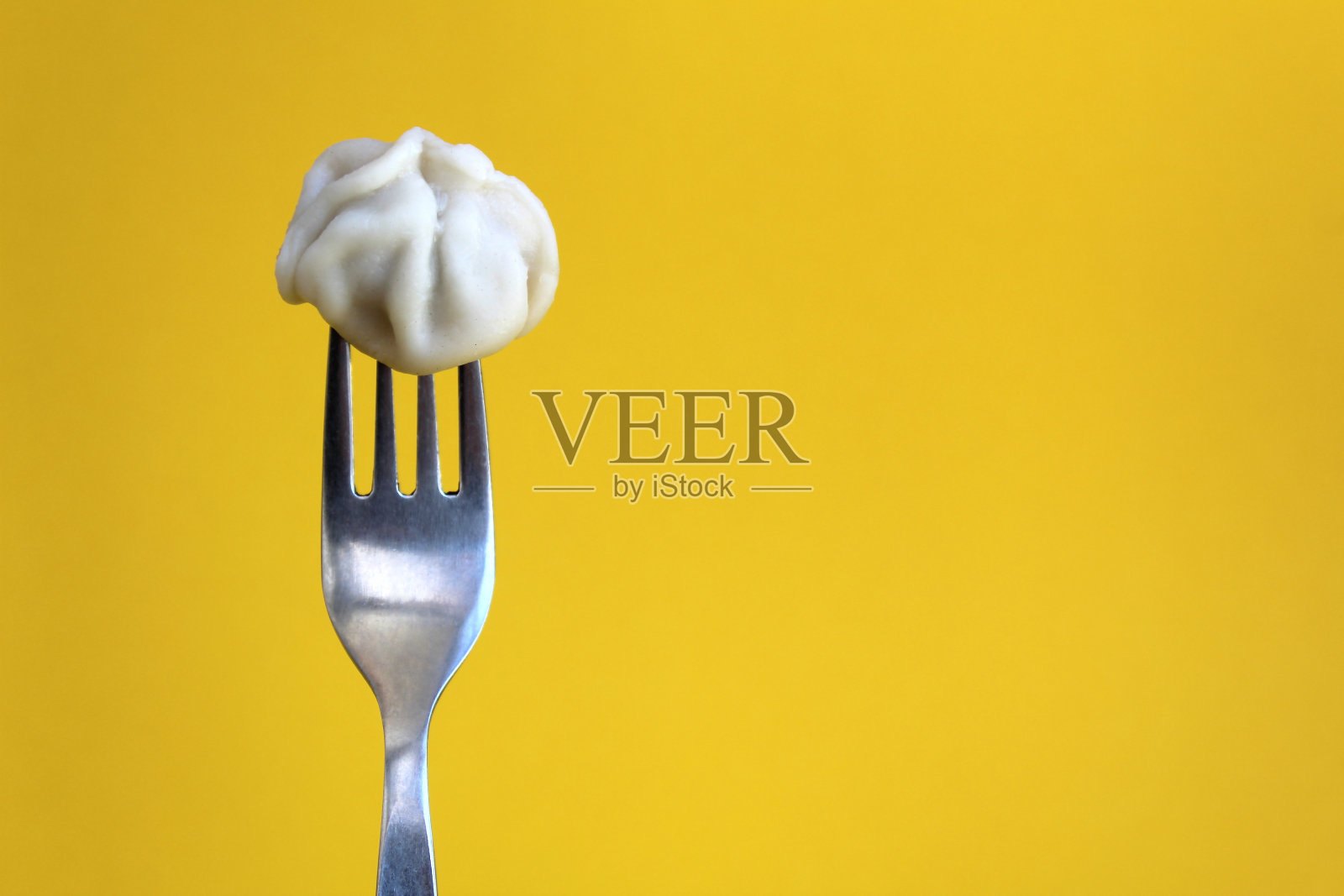 美味的肉一个饺子刺在叉子上在黄色的背景照片摄影图片