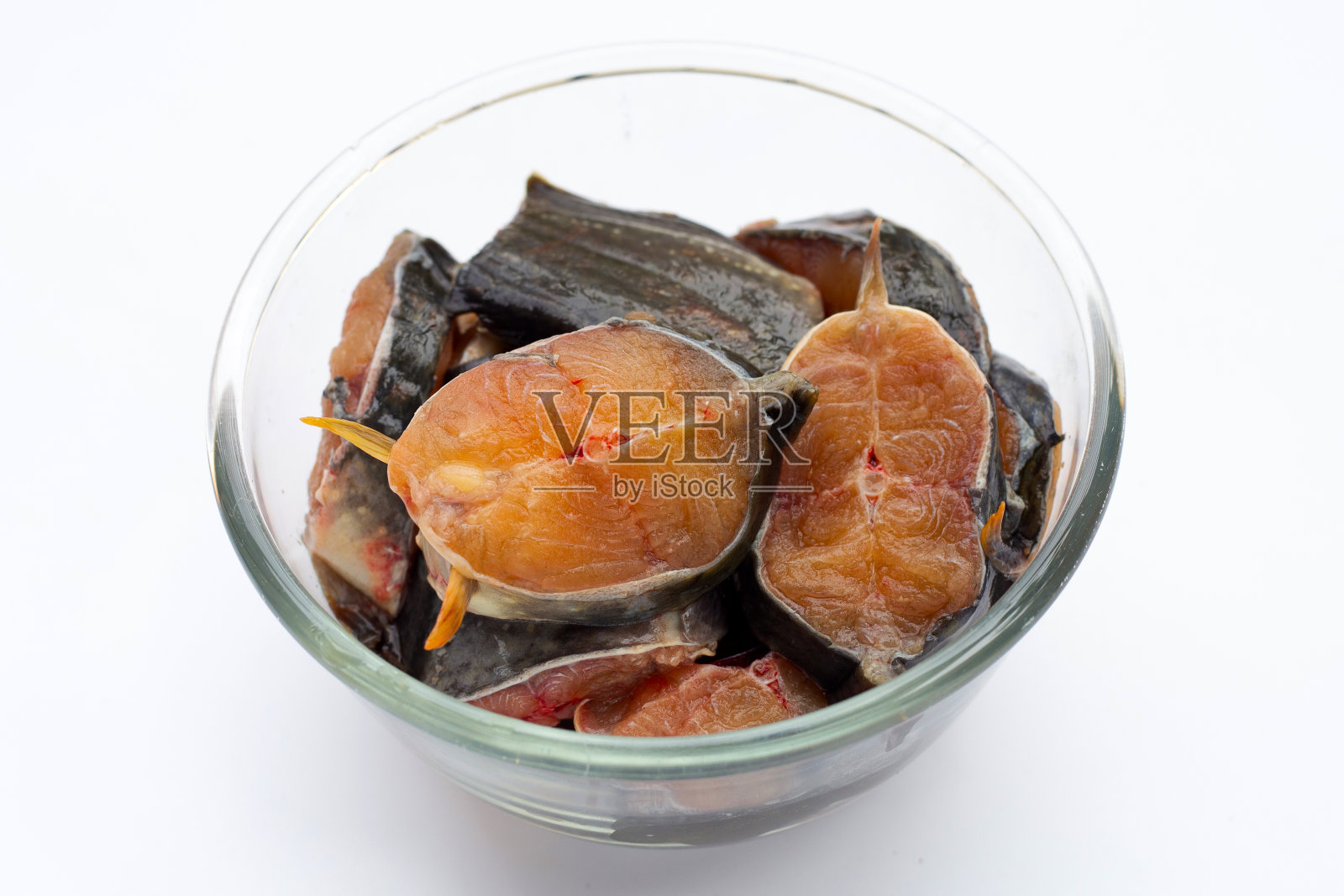在白色背景的玻璃碗里切鲶鱼片。照片摄影图片