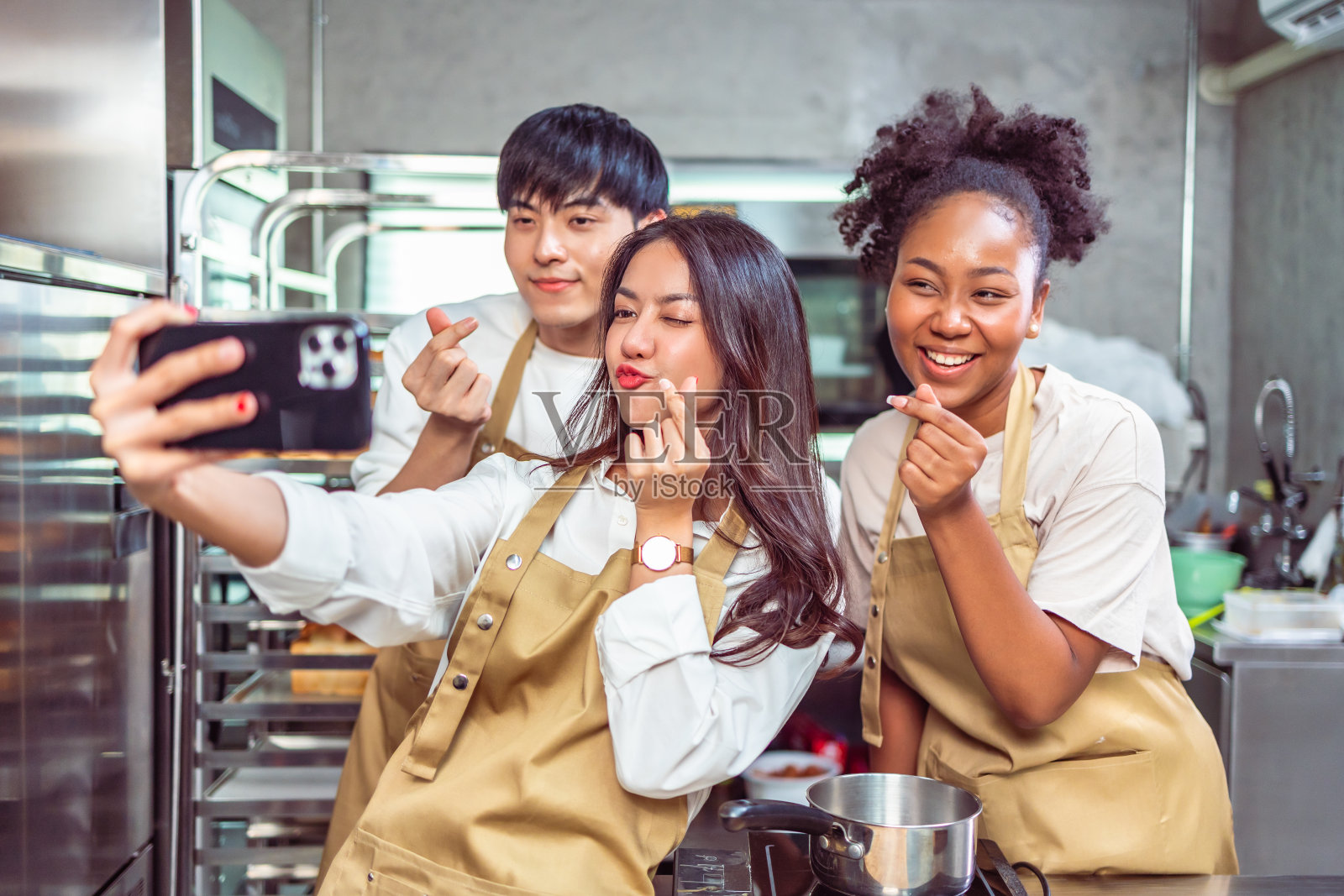 烹饪课的学生在厨房里为食谱混合配料。一群年轻人在烹饪课上自拍。照片摄影图片