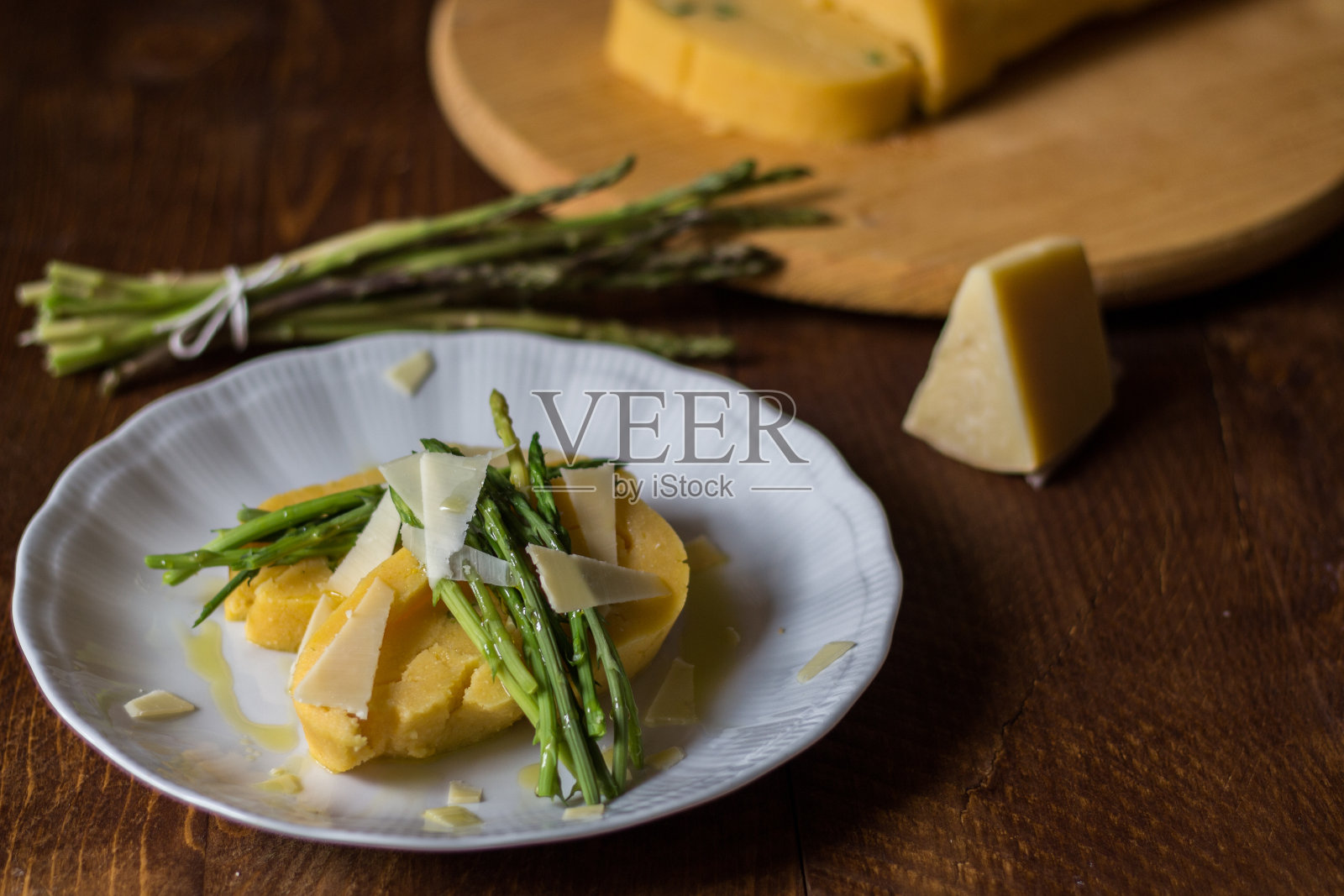 玉米粥卷芦笋和奶酪片在白色的盘子和深色的木材背景照片摄影图片