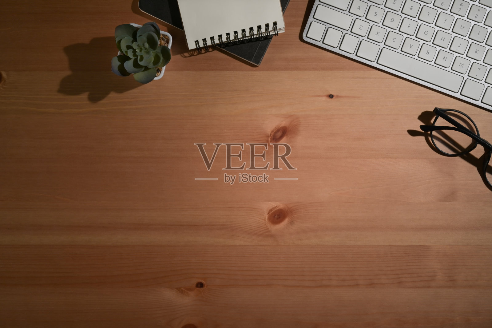 上面查看无线键盘,眼镜和记事本的木制背景。照片摄影图片