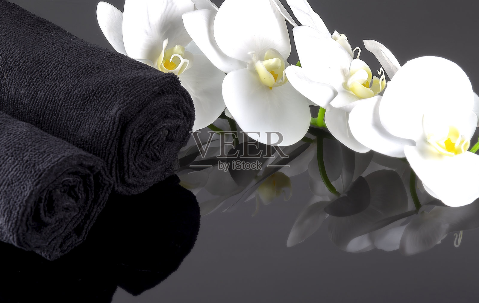 黑色浴巾和漂亮的白色兰花。有水疗和健康背景。照片摄影图片