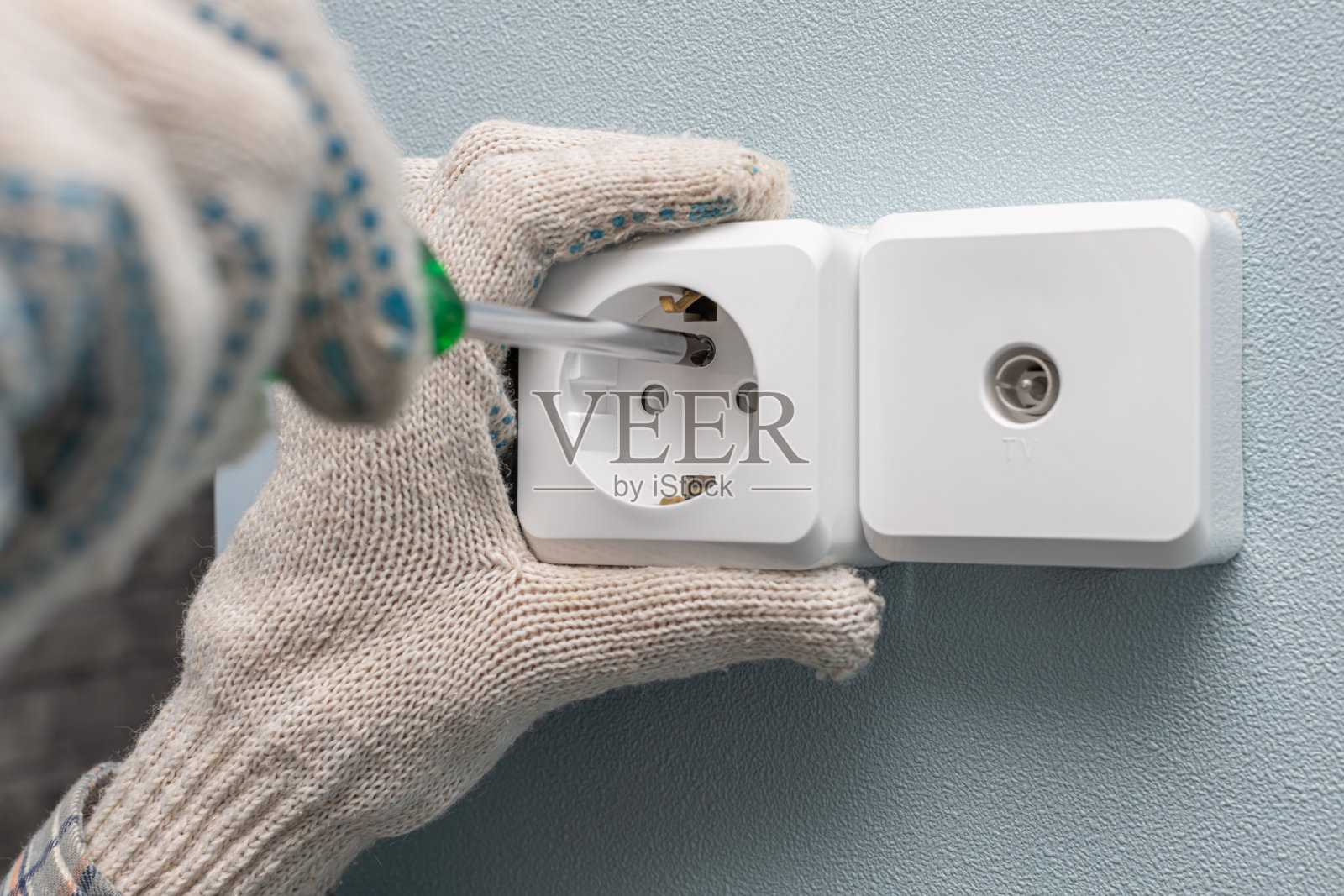 一个人用螺丝刀拧墙上的电源插座照片摄影图片