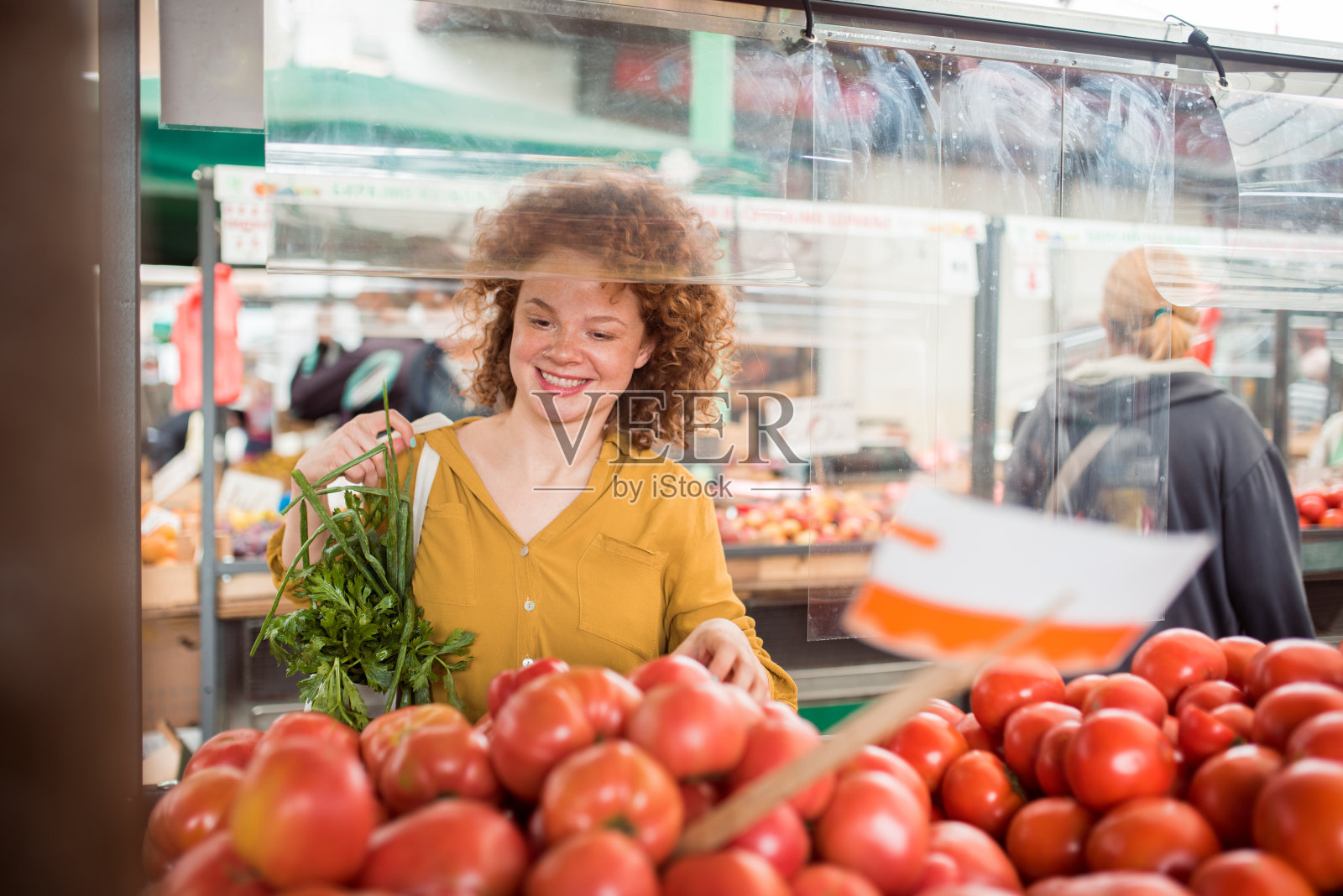 漂亮的红发女孩在市场上买西红柿照片摄影图片