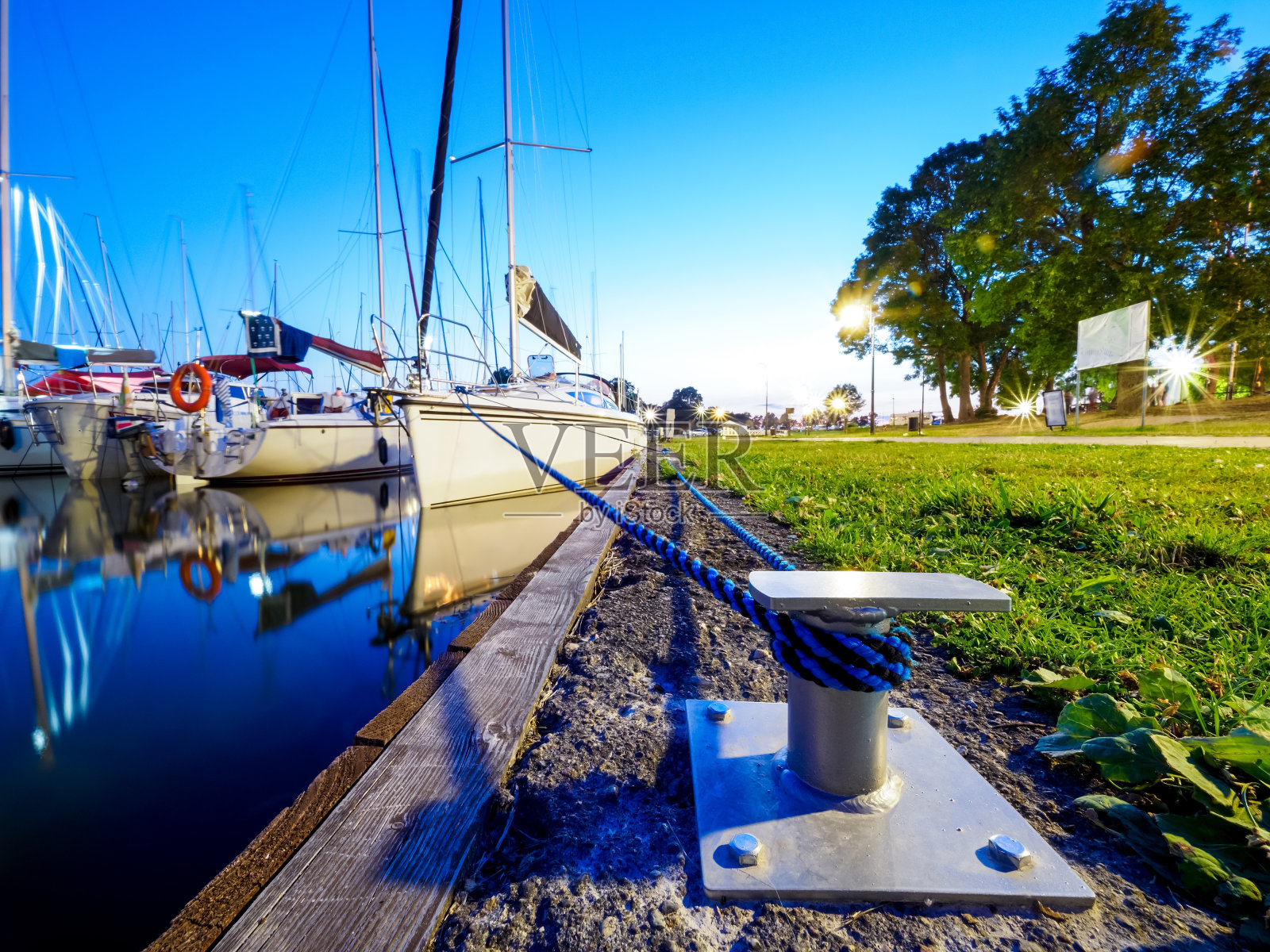 在金属系柱或钩码头停泊的帆船,平静的夏季黄昏的看法在一个港口的湖照片摄影图片