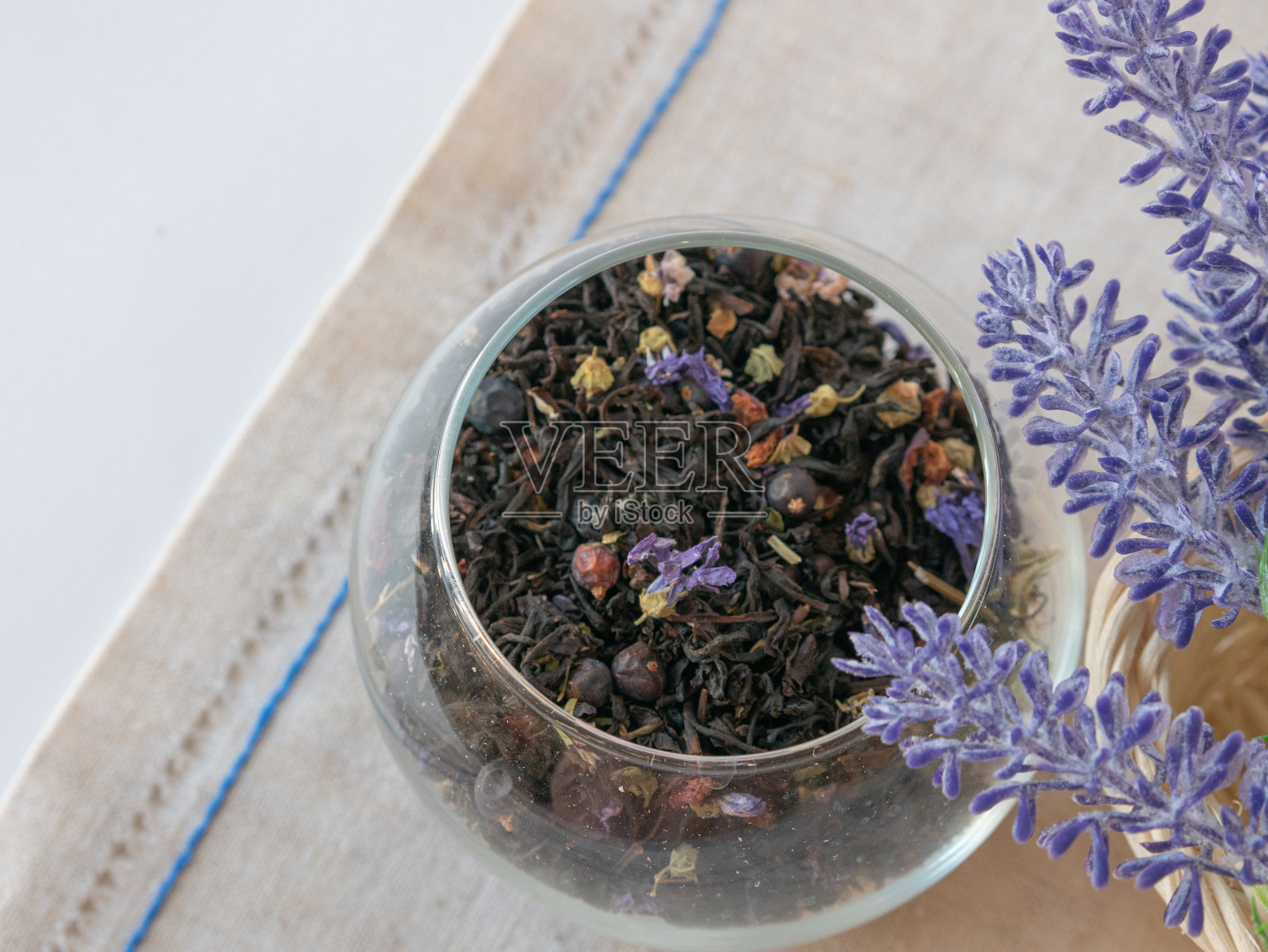 草药茶,蓝色干花,圆玻璃花瓶,帆布餐巾,薰衣草花照片摄影图片