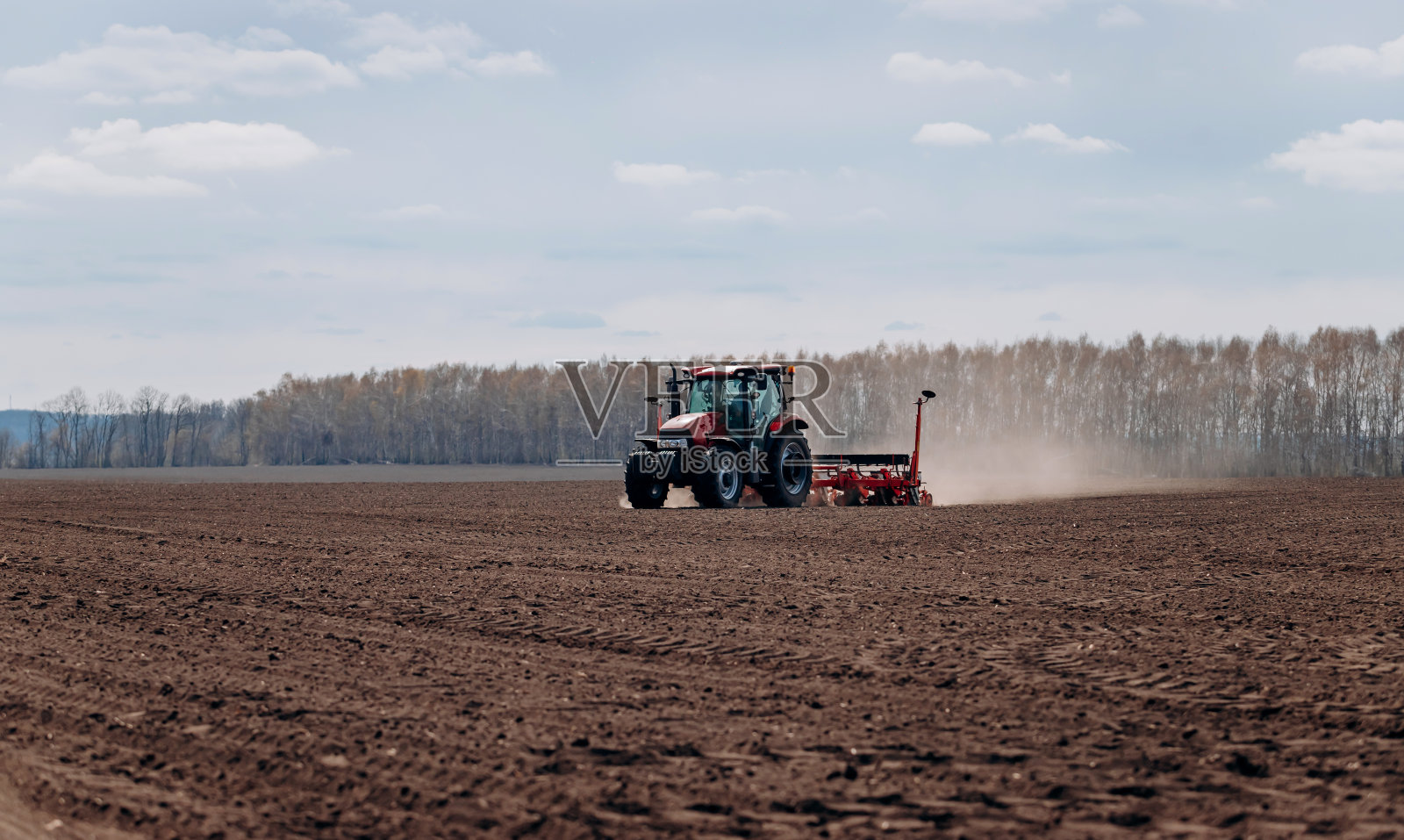 春天播种的季节。一个农夫用拖拉机在田里播种玉米种子。用牵引式播种机种植玉米照片摄影图片