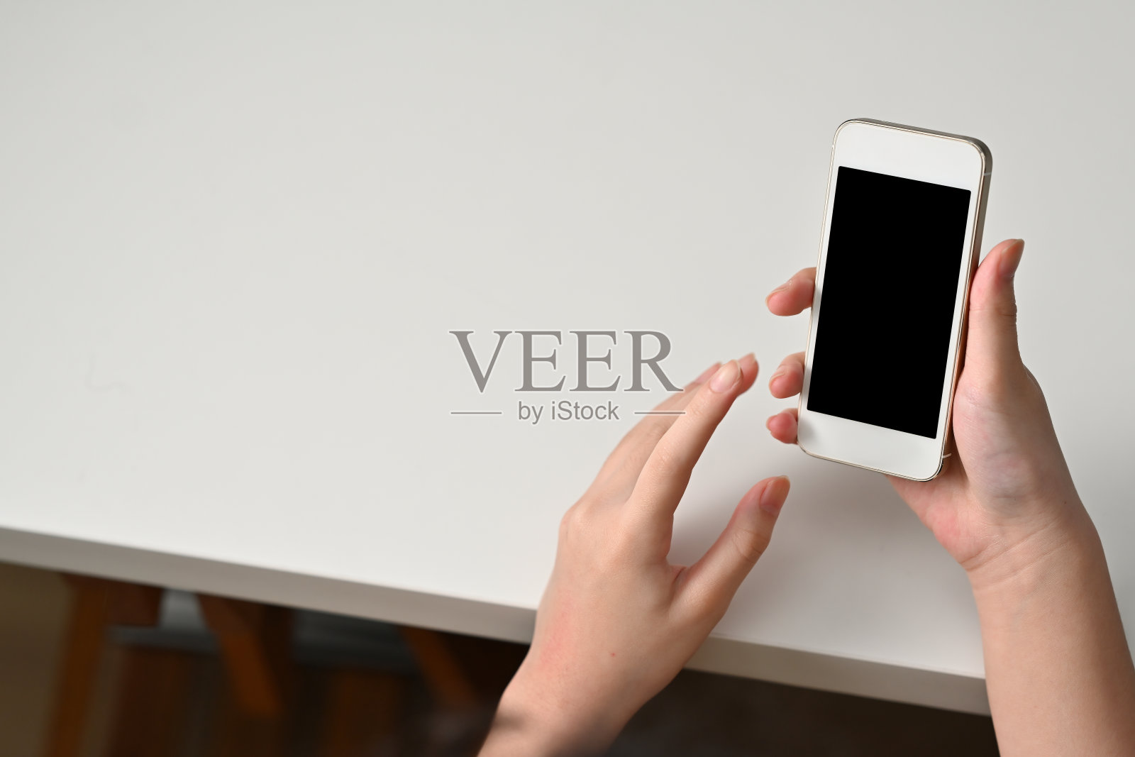 俯视图的青少年手拿着一个黑色屏幕的智能手机。照片摄影图片