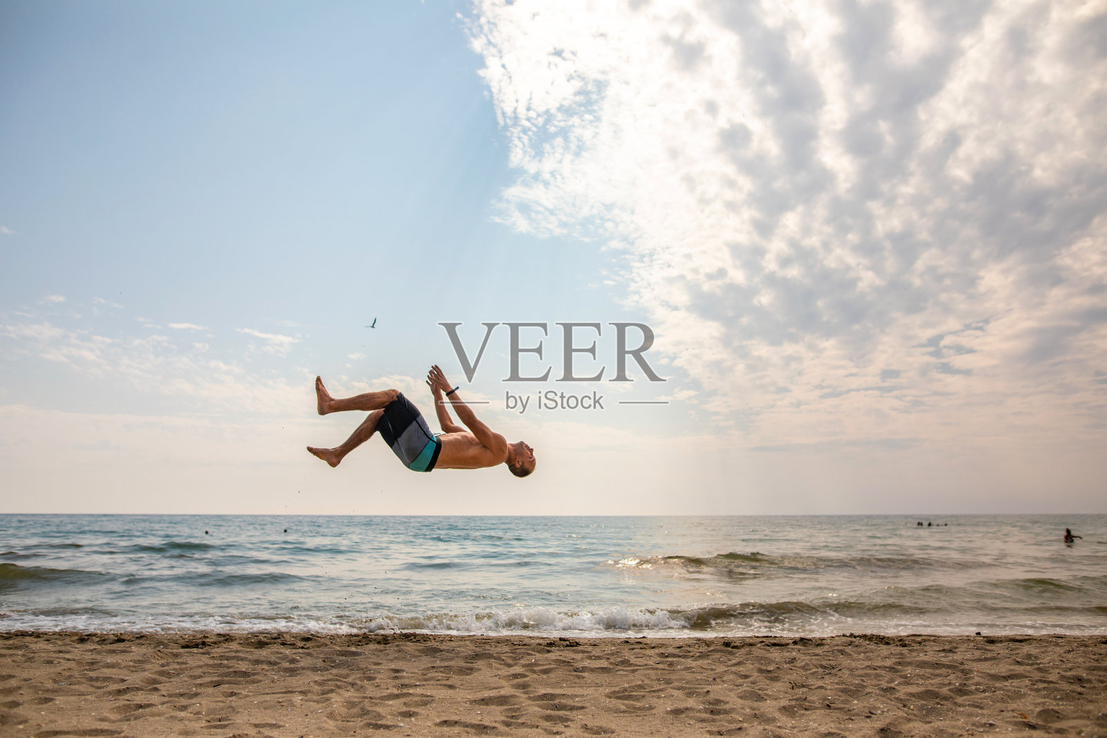 在海滩上做后空翻的白人男子照片摄影图片