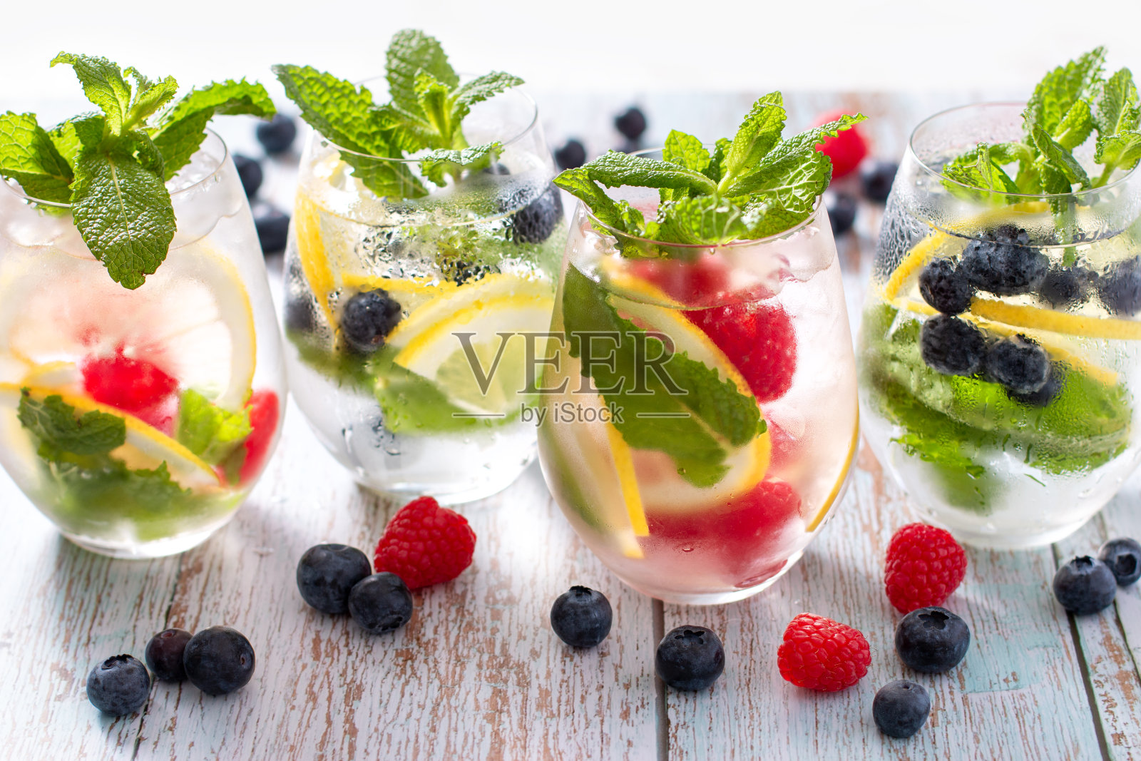 树莓、柠檬和黑莓在木桌上的玻璃杯中注入水照片摄影图片