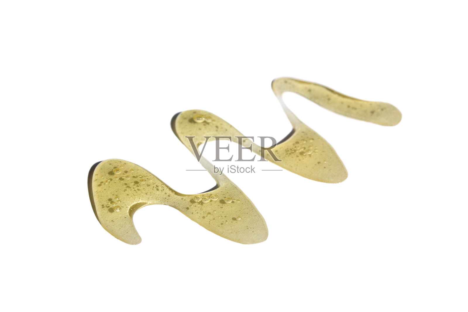 金色的蜂蜜以锯齿的形式洒在白色的背景上。照片摄影图片