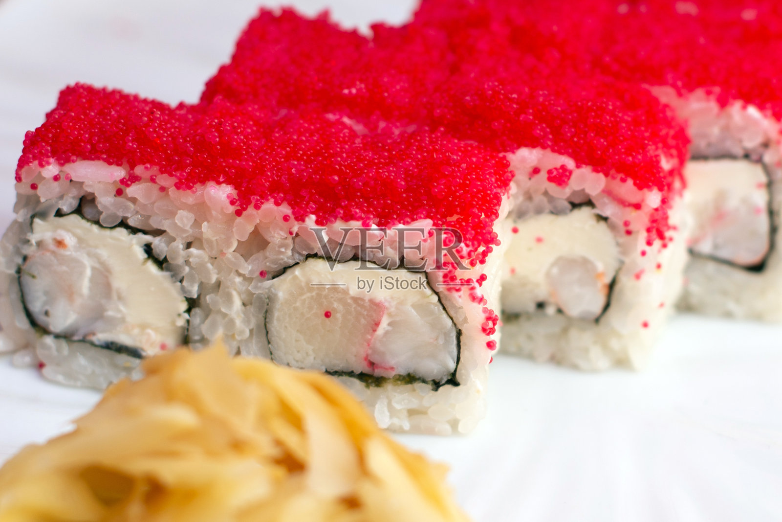 白色背景下的红色鱼子酱和黄瓜寿司卷,特写照片摄影图片