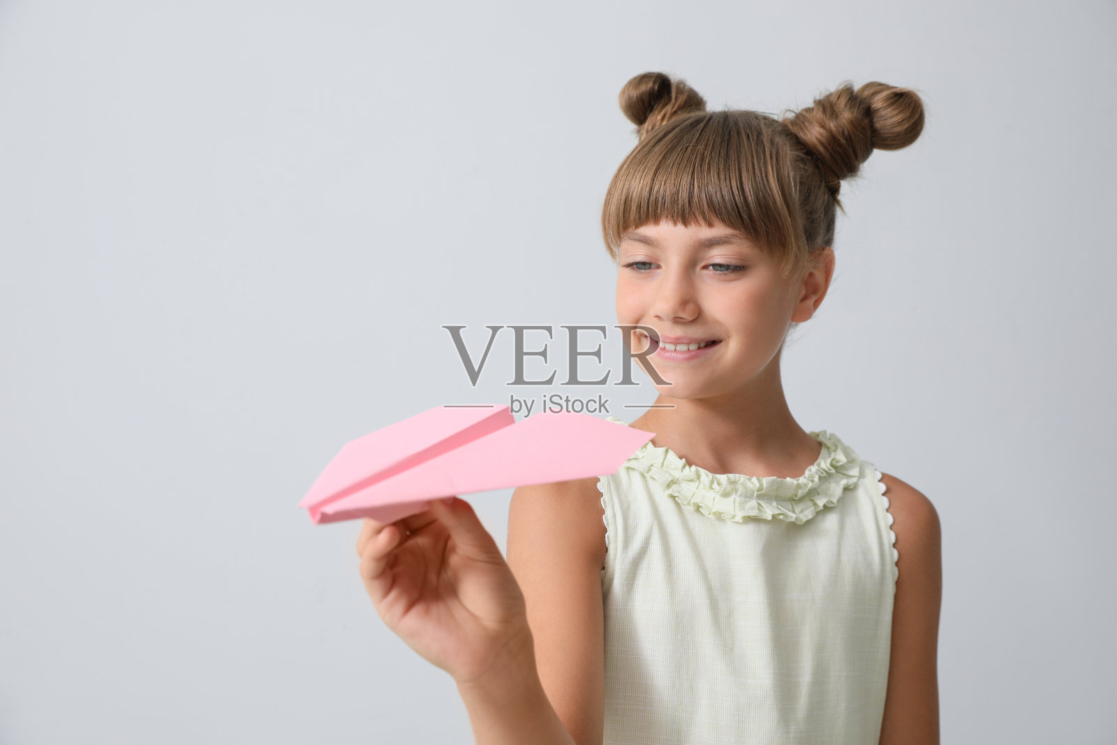 可爱的小女孩在浅灰色的背景下玩纸飞机照片摄影图片