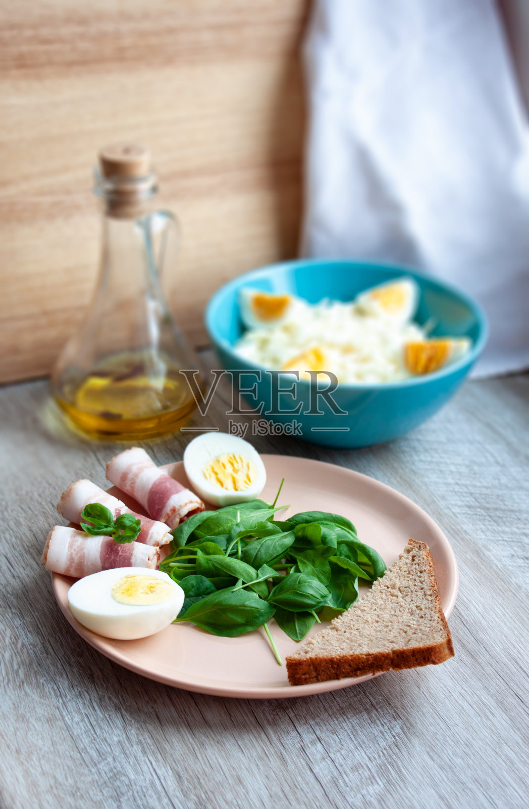 食物。健康的早餐。盘子里有菠菜叶,绿色罗勒,培根,鸡蛋和一片黑麦面包。卷心菜鸡蛋沙拉。香辣的橄榄油和胡椒粉。有选择性的重点照片摄影图片
