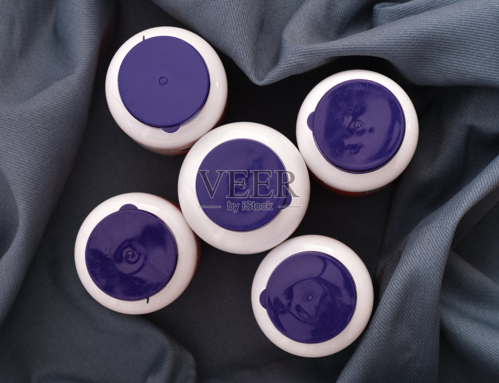 五个维生素瓶,蓝色瓶盖,深蓝色背景。照片摄影图片