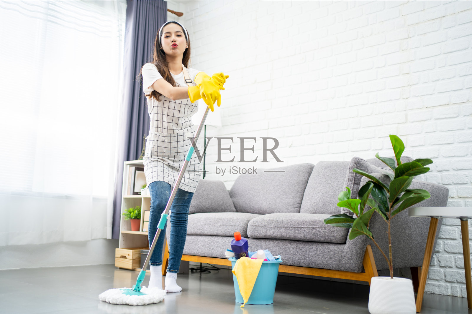 一个美丽的亚洲年轻女子的全长身体尺寸的看法谁是专业清洁的房子在客厅。照片摄影图片