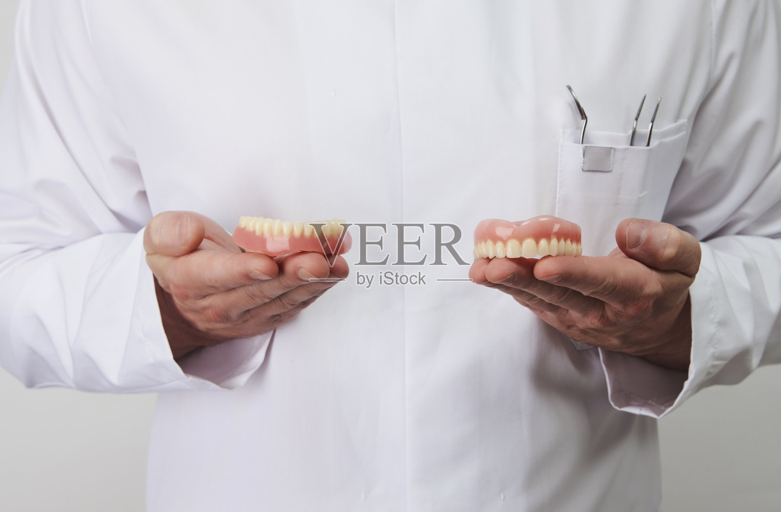 年轻的牙医持有牙齿颌在白色背景照片摄影图片