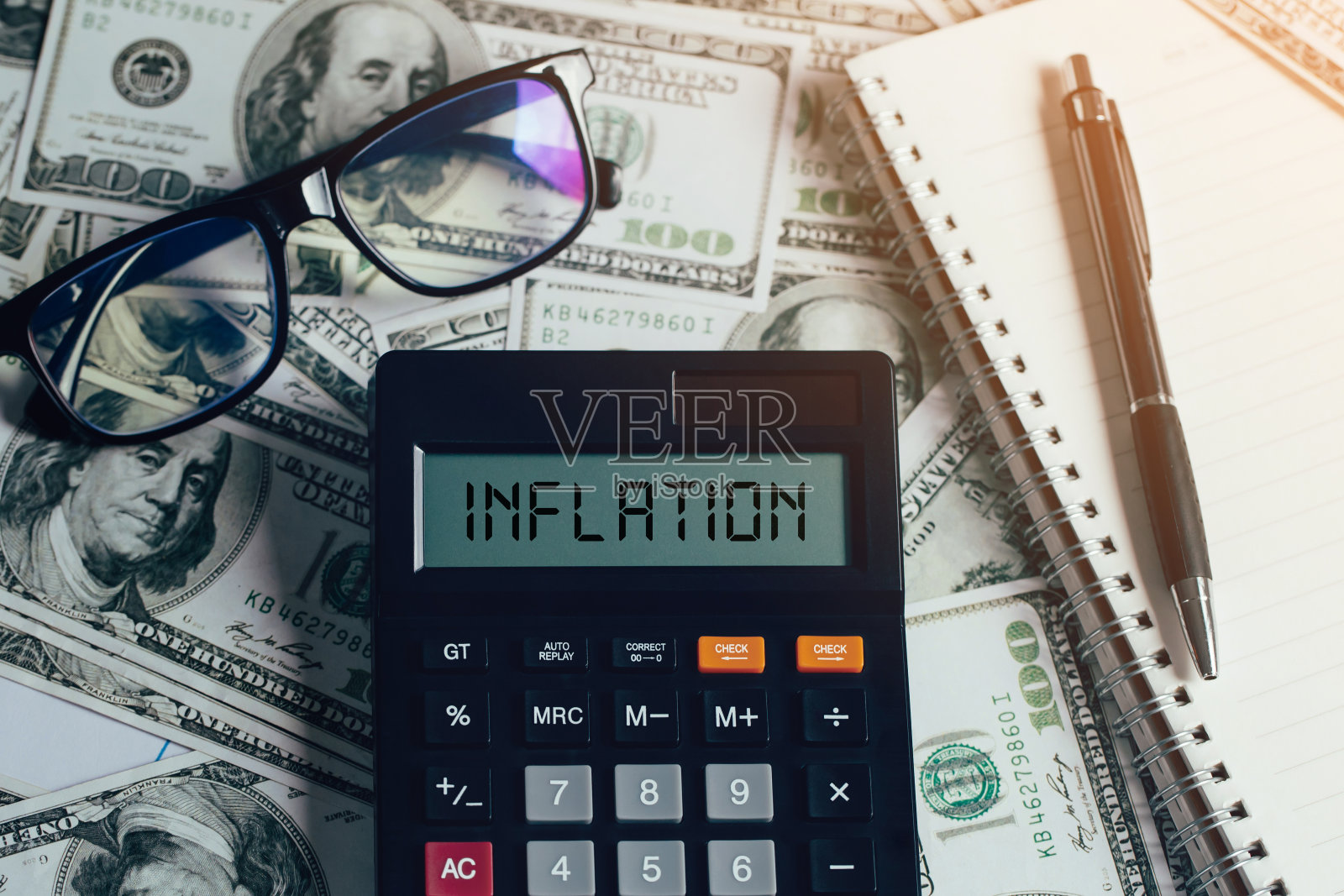 钞票上的计算器上印着“通货膨胀”字样,戴着眼镜,笔记本上印着笔。美联储的概念考虑的是加息、世界经济、通货膨胀控制、美元通货膨胀照片摄影图片