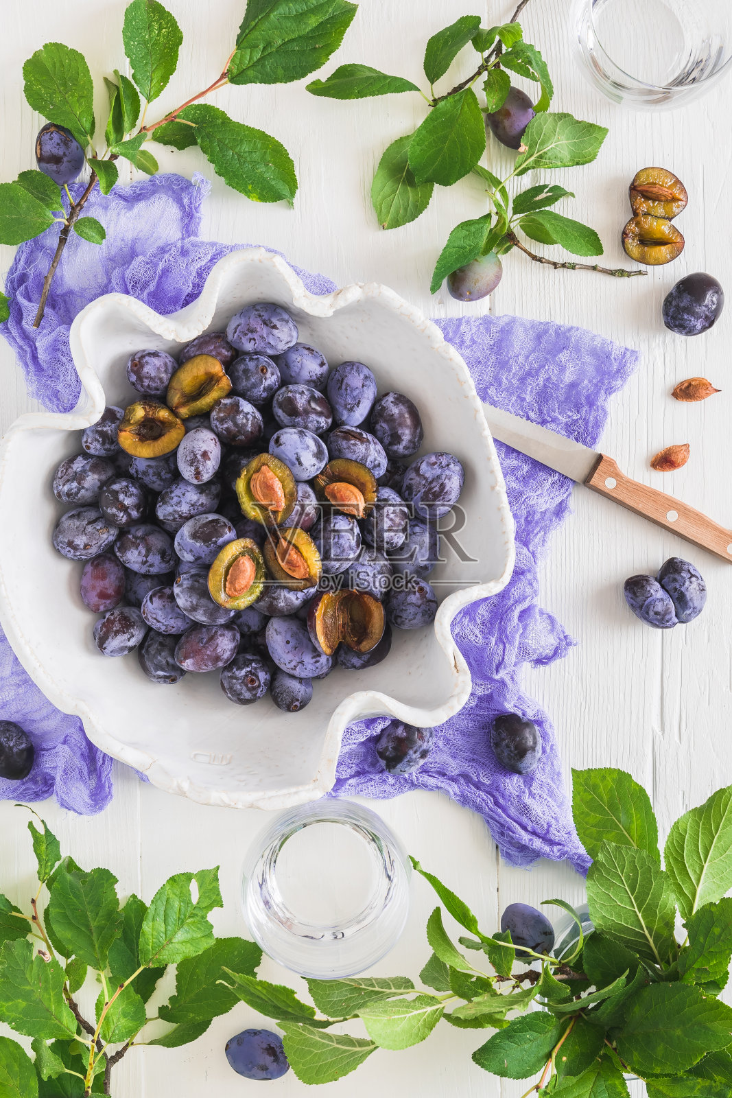 白色的手工碗里装满了成熟的李子,有些是切片的照片摄影图片