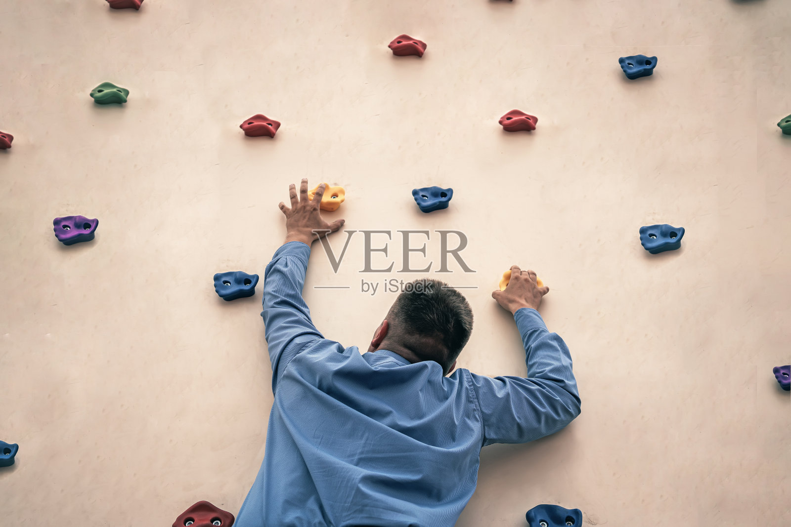 打着领带的商人在攀岩。把攀岩作为业余爱好。办公室职员在健身房训练。极限运动。照片摄影图片