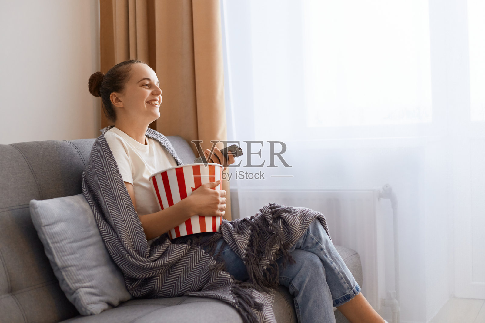 裹着毯子在沙发上看电视的快乐女性的横版照片照片摄影图片