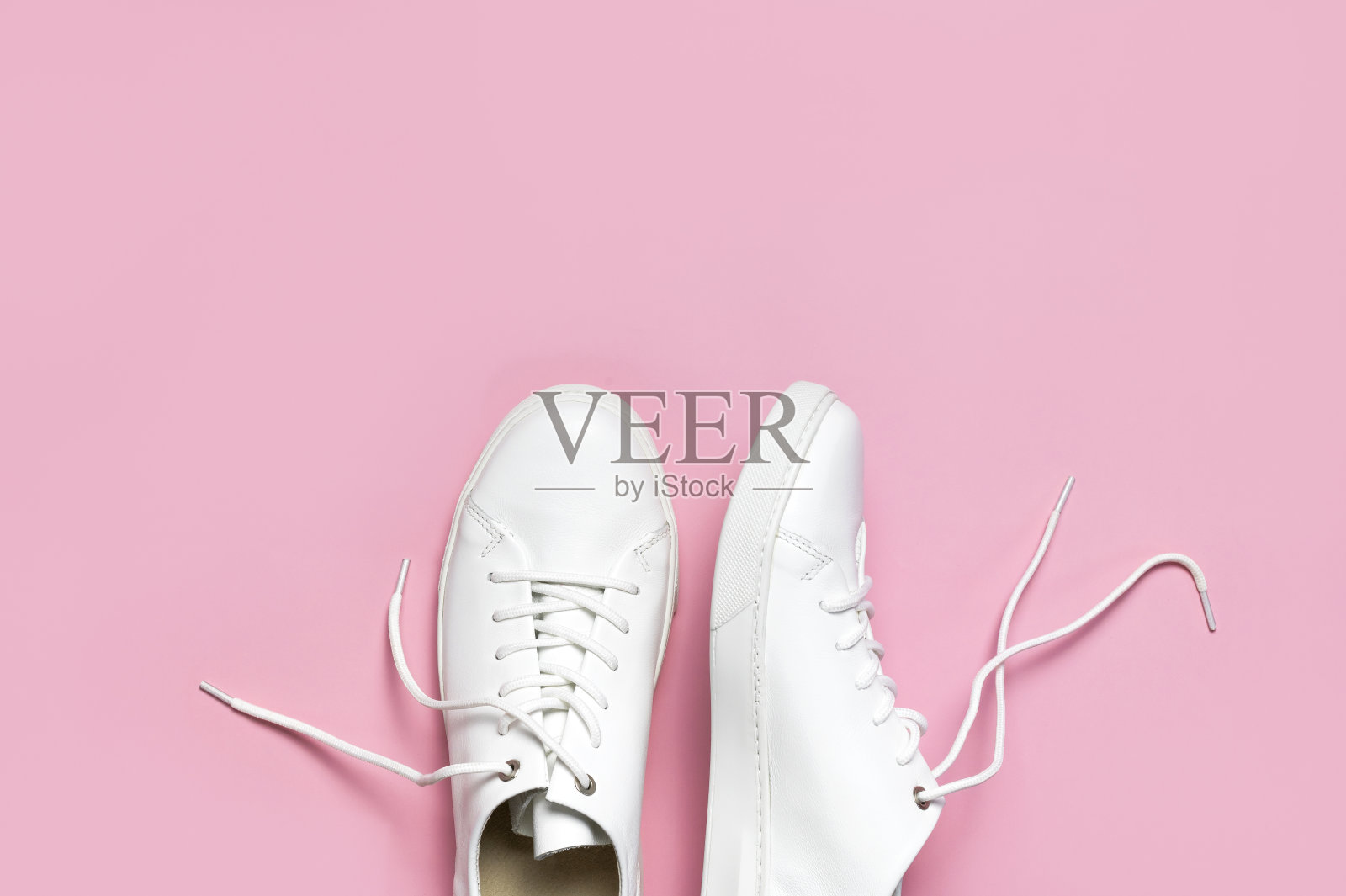 白色妇女的皮革运动鞋在粉红色背景顶视图平lay。时尚青年运动鞋,运动鞋,真皮鞋履。简约的鞋店广告时尚风格的鞋子背景照片摄影图片