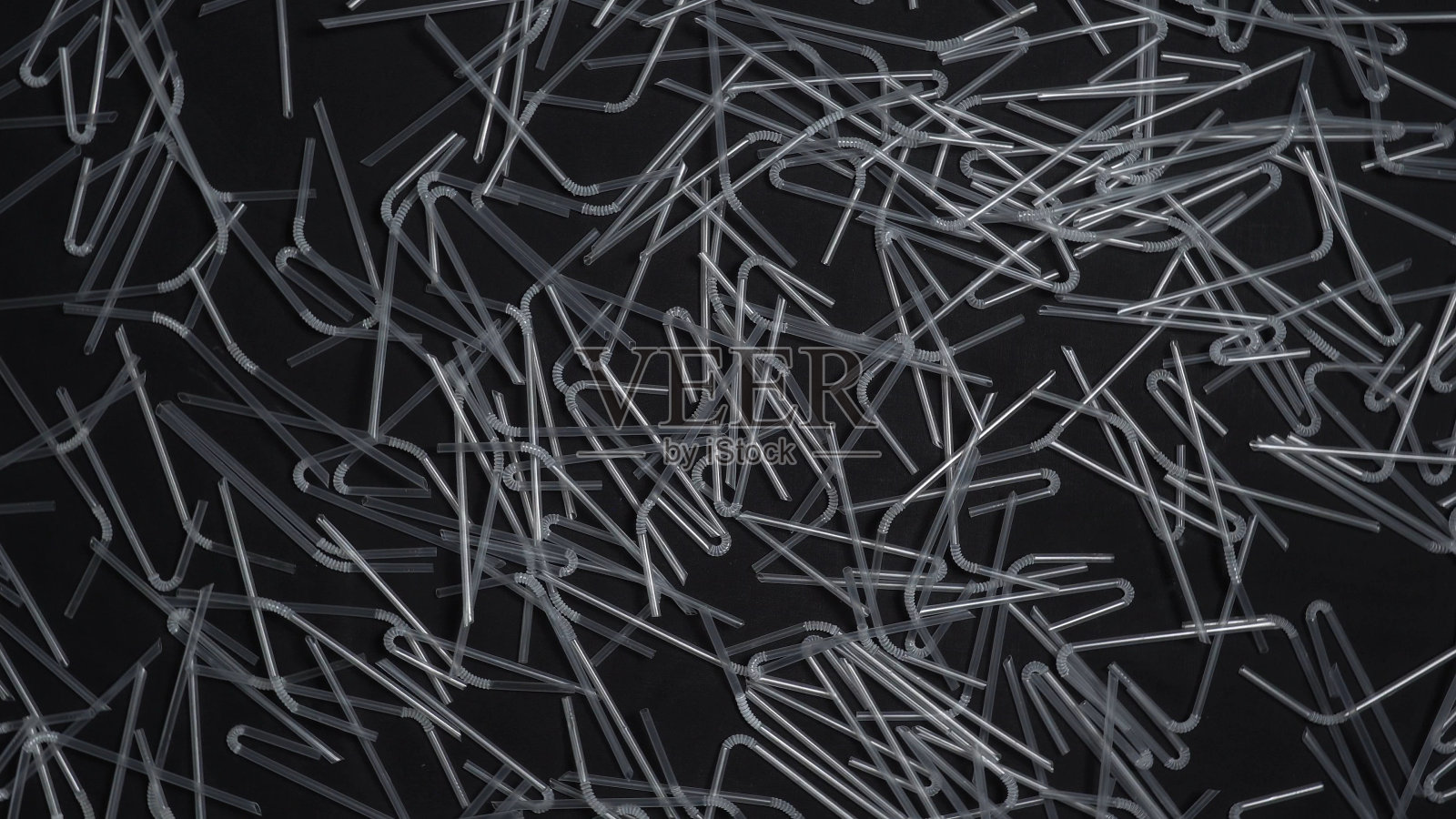 塑料秸秆垃圾收集。鸡尾酒果汁塑料吸管在黑色背景上缓慢旋转。塑料垃圾环境污染问题。没有一次性塑料和生态概念。照片摄影图片