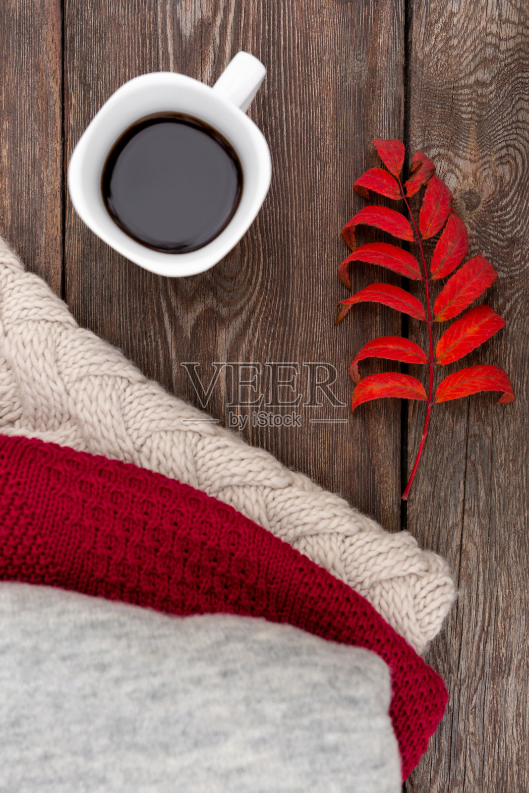 秋天的背景或明信片。白杯子里的咖啡,放在木凳上。秋叶和暖毛衣照片摄影图片
