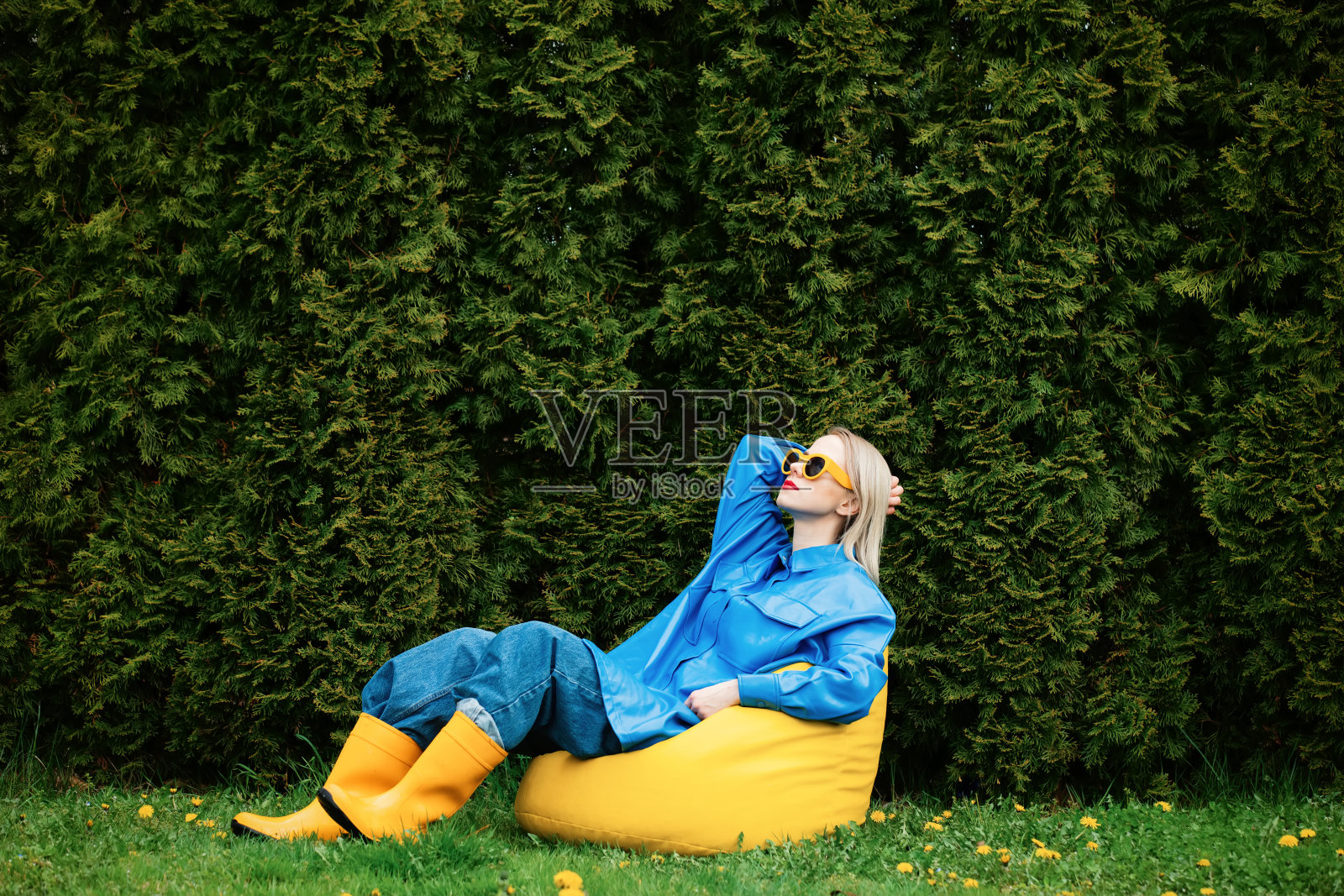 乌克兰妇女在春天的花园里穿着蓝色衬衫和黄色靴子照片摄影图片