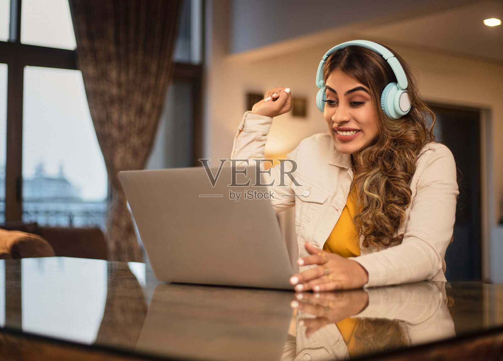 一个年轻的现代漂亮的亚洲印度女人或女孩正在观看在线直播的板球或足球比赛在笔记本电脑上照片摄影图片