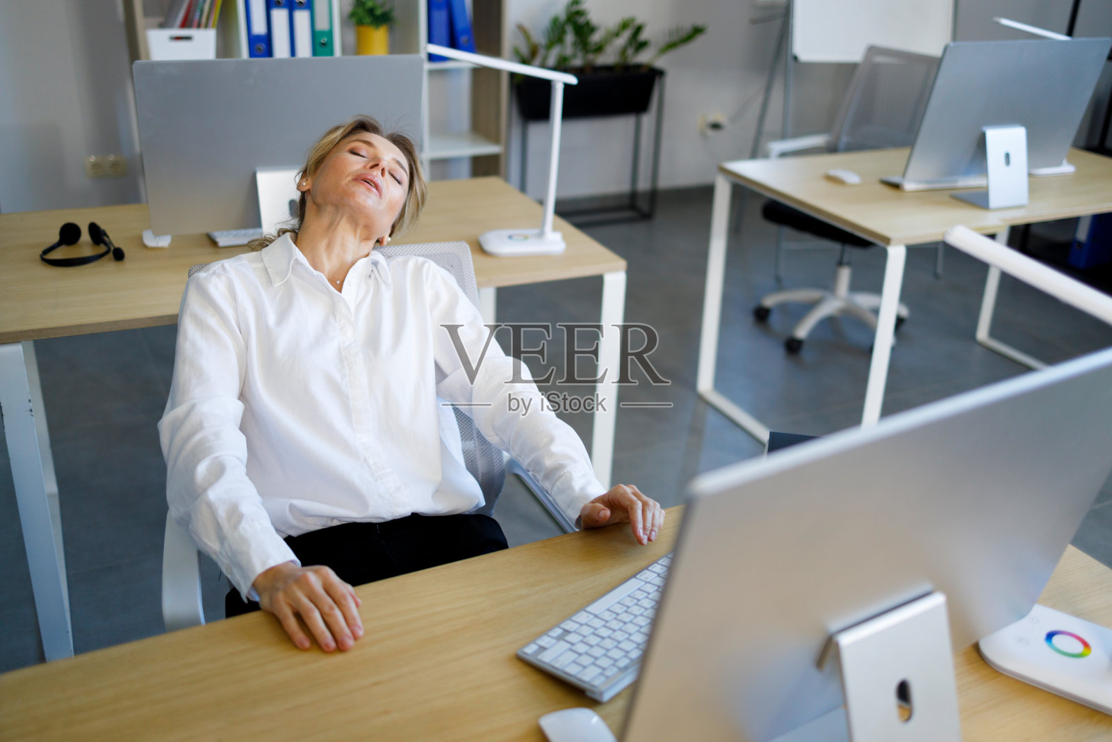 成熟的女商人,在电脑前长时间工作后,在办公室里休息和伸展脖子照片摄影图片