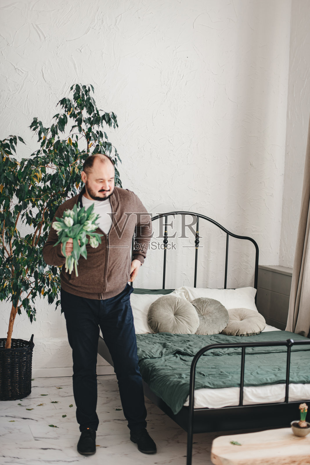 一个男人手里拿着一束花,在室内。照片摄影图片