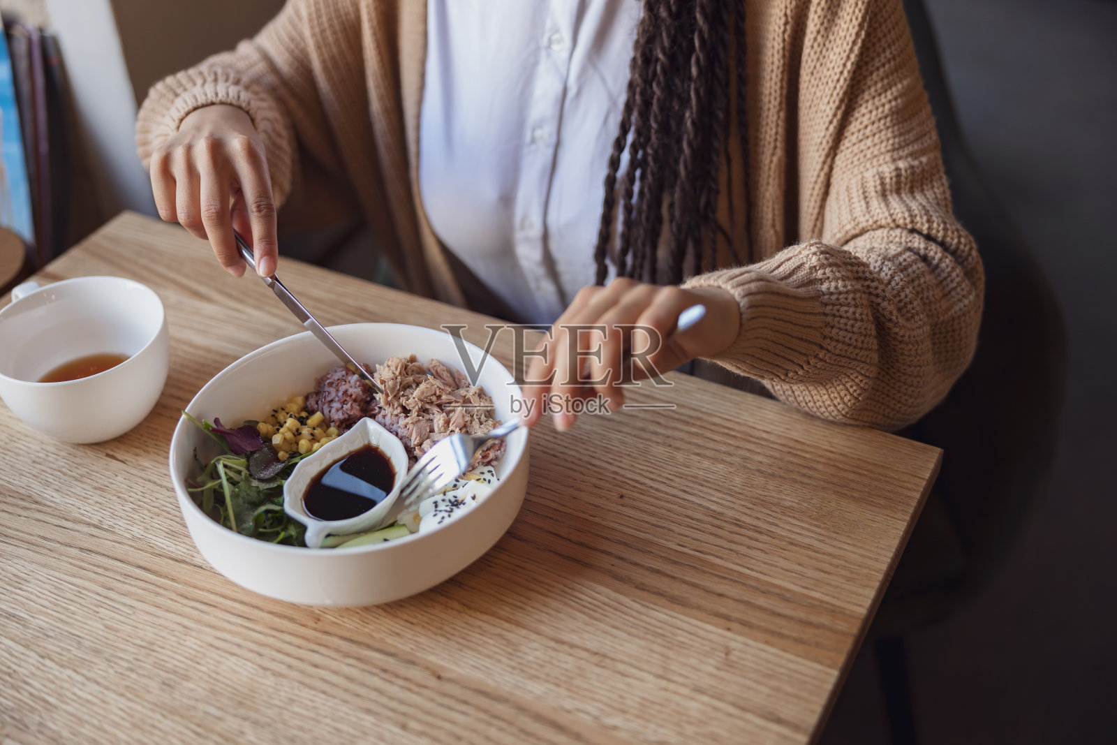 特写的咖啡馆客人拿着餐具和品尝美味的健康食品服务在餐厅的白色陶瓷碗照片摄影图片