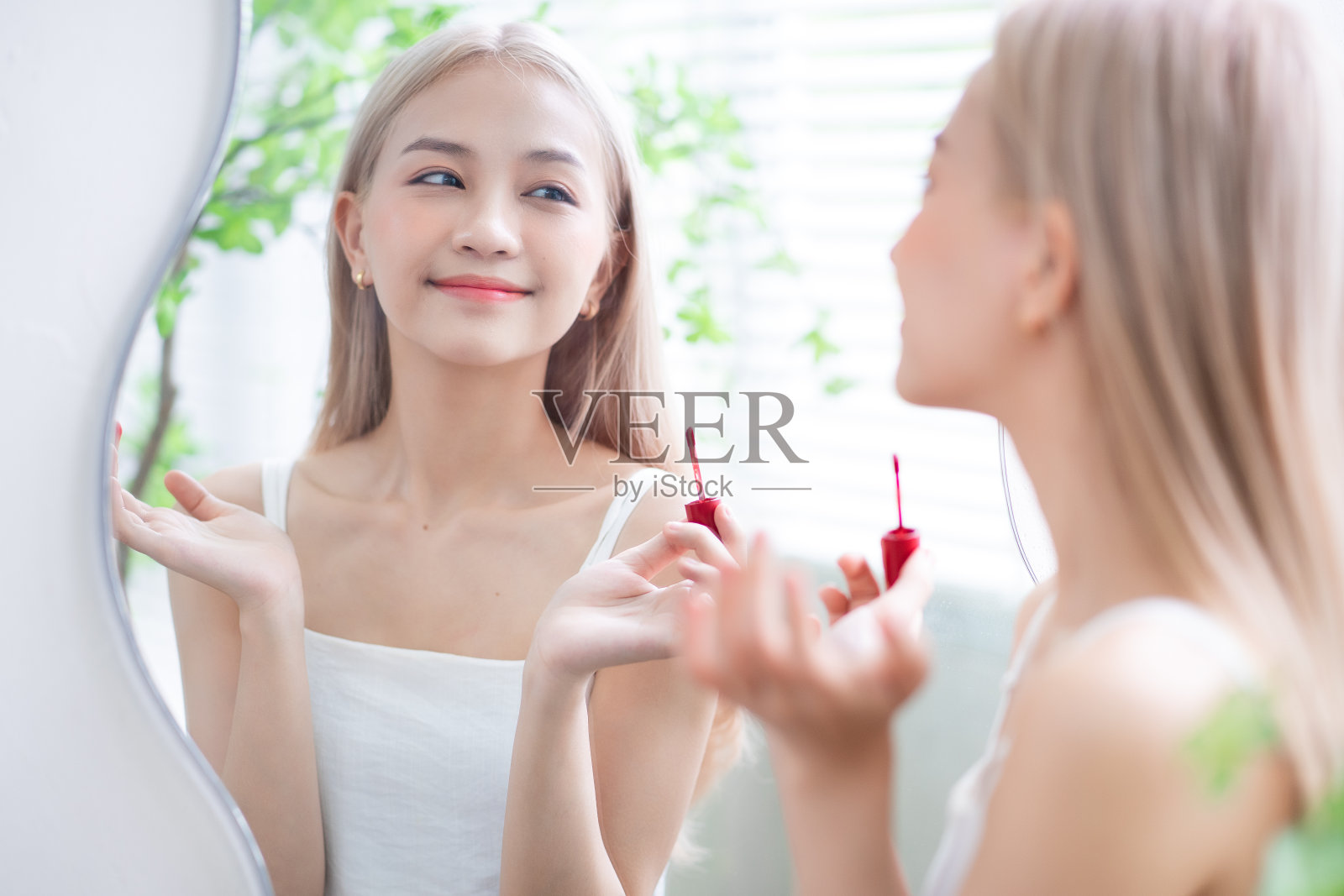 年轻的亚洲女子在镜子前涂口红照片摄影图片