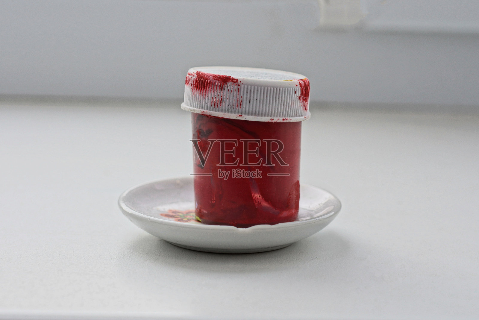 一个白色的、脏兮兮的、封闭的、涂着红色油漆的塑料罐子照片摄影图片