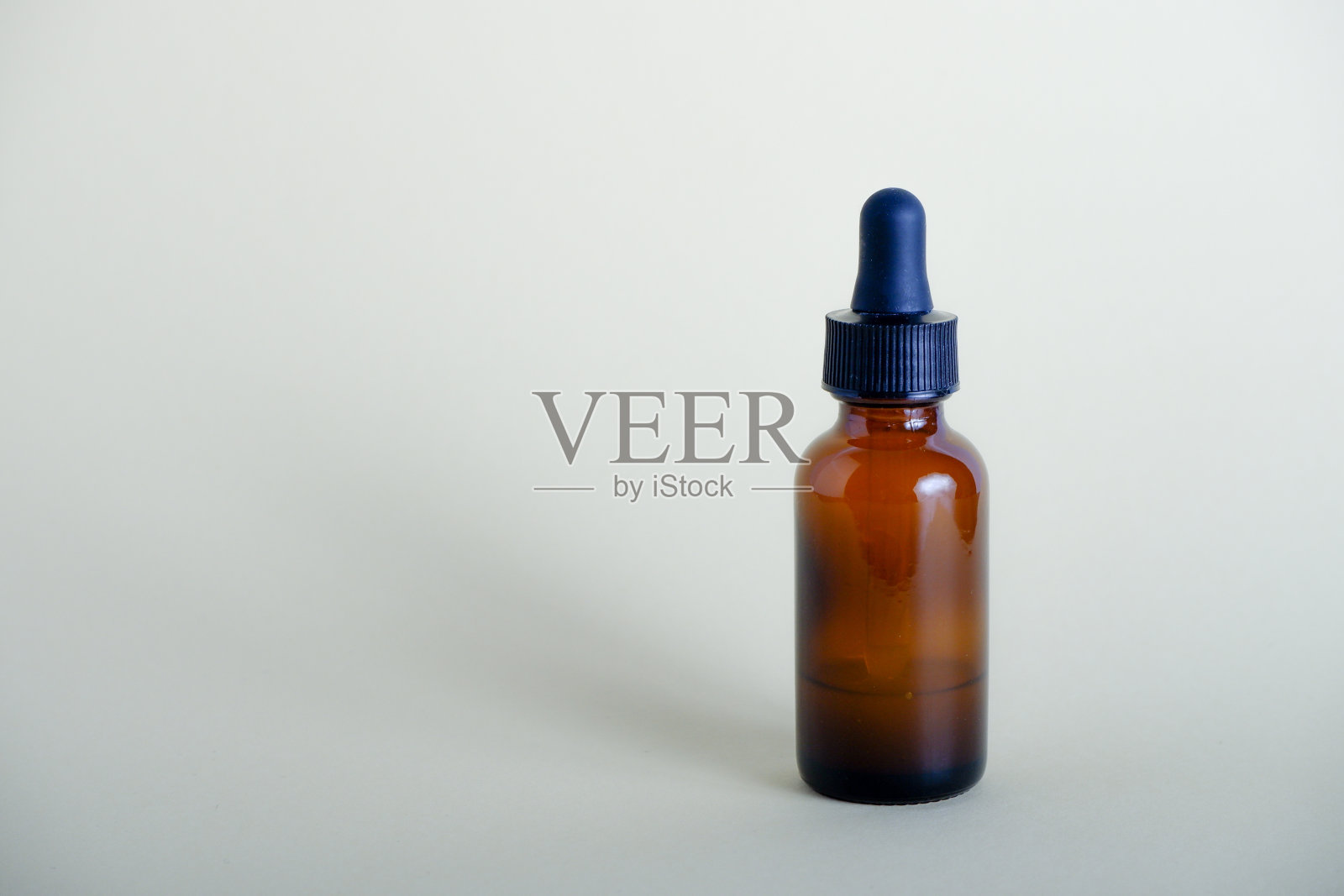 精华油琥珀滴管瓶。米色背景带移液管的血清玻璃瓶。天然有机液体药物或化妆品油。照片摄影图片