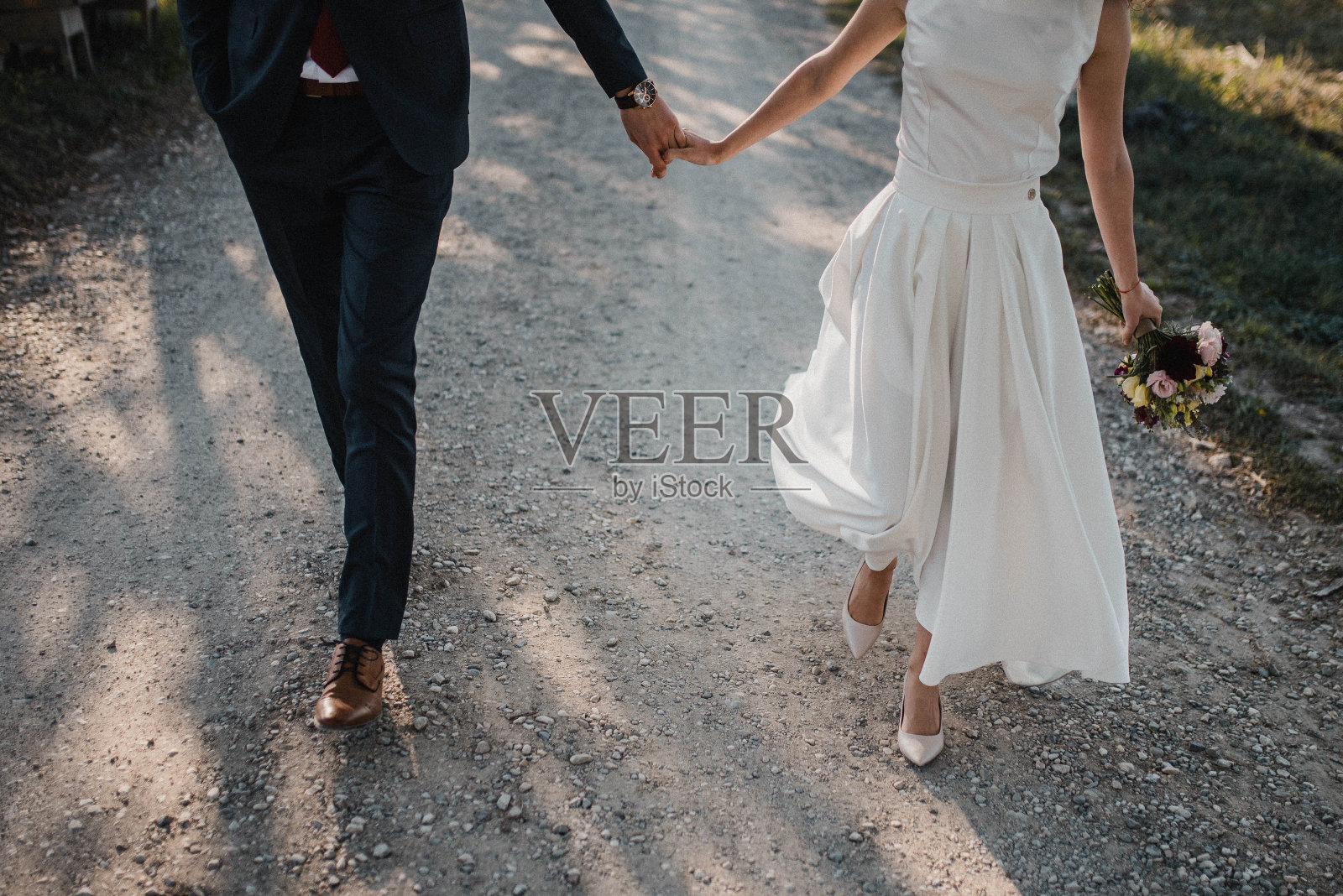 新娘身着美丽的白色婚纱,手捧花束,新郎身着优雅的西装,在新婚快乐的日子。照片摄影图片