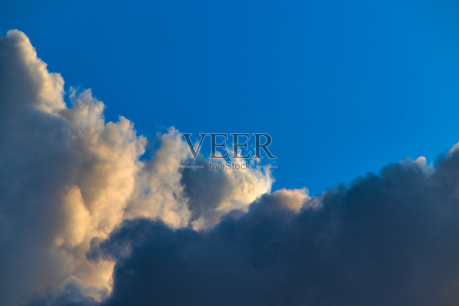 两朵积云分开了蓝天的地平线。照片摄影图片