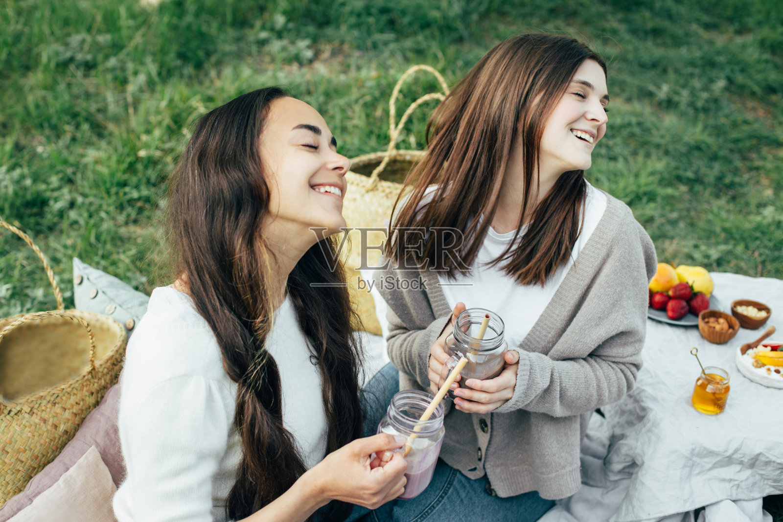 两个快乐的年轻女人在公园野餐。照片摄影图片