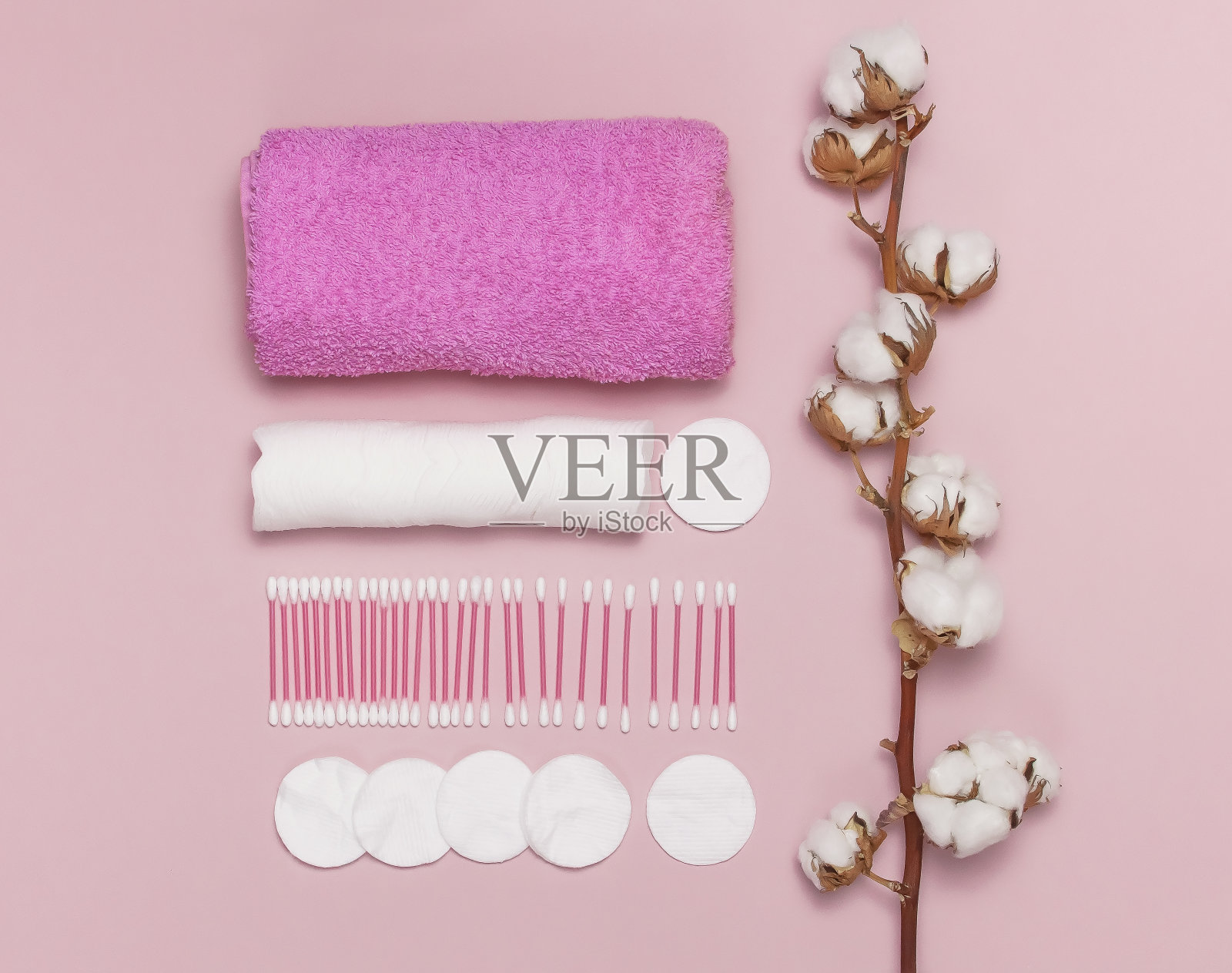 水疗中心的概念。平铺背景棉枝,棉垫,耳棒,粉红色毛巾。棉花化妆品卸妆卫生棉条。粉红色背景上的卫生棉签俯视图照片摄影图片