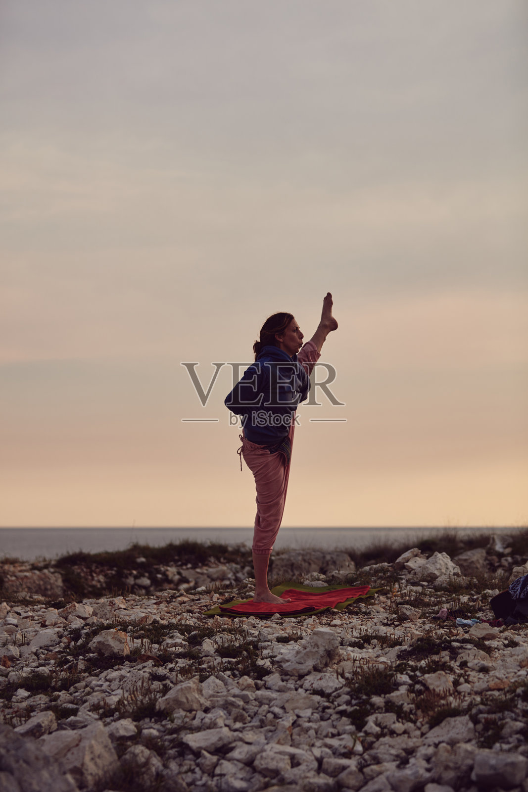 女人在日落日出的时候练习瑜伽。照片摄影图片