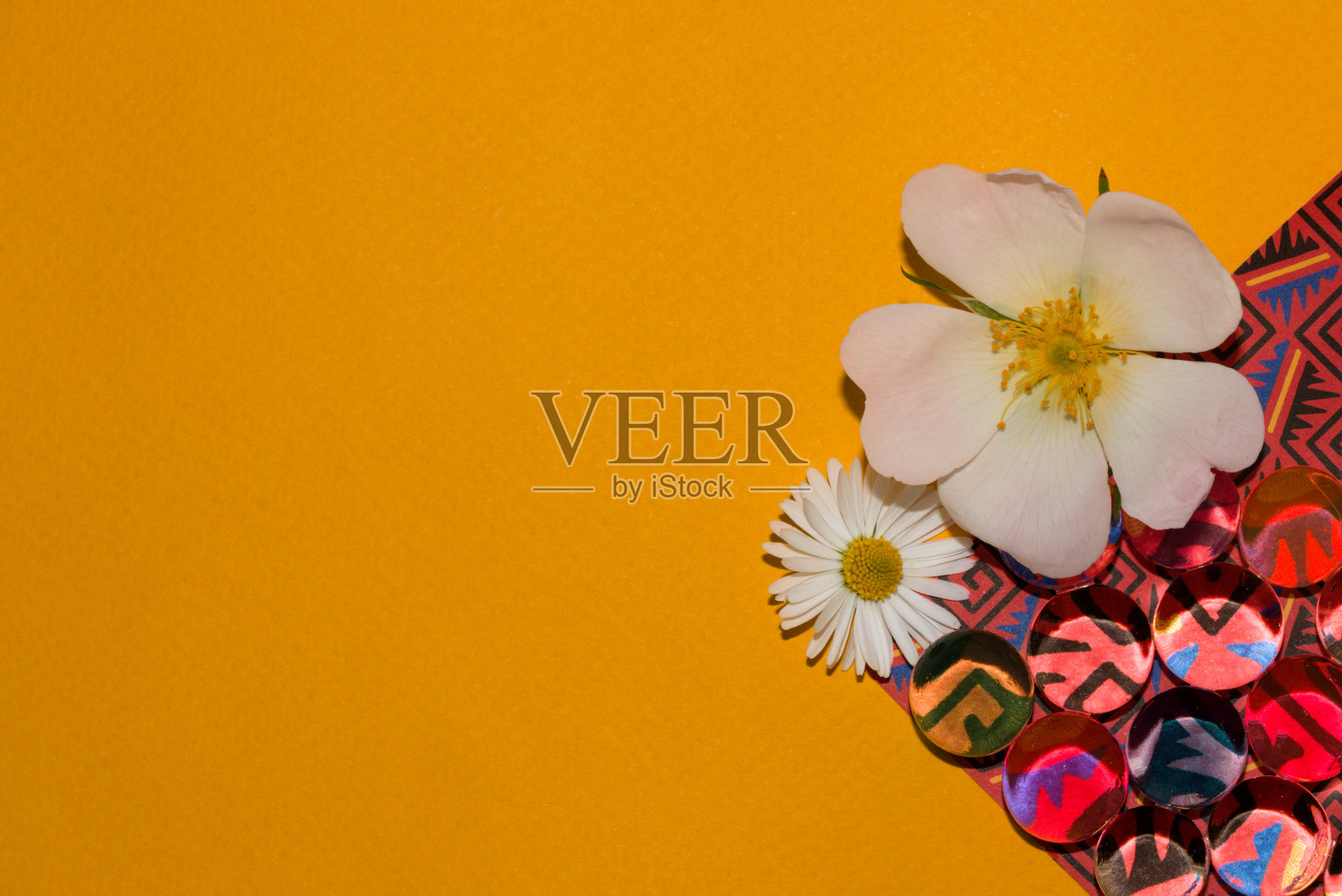 彩色的复古墙纸,透明的珠子和黄色背景上的两个花头作为拷贝空间照片摄影图片