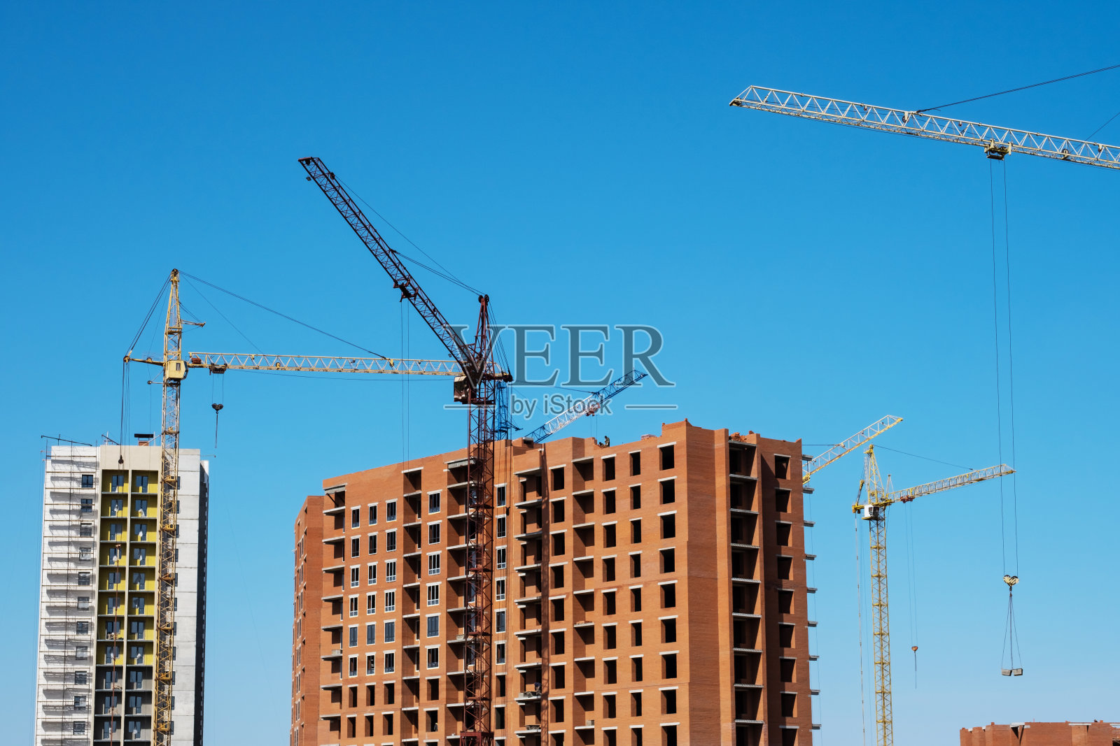 蓝天下建筑工地上的塔吊和在建楼房照片摄影图片