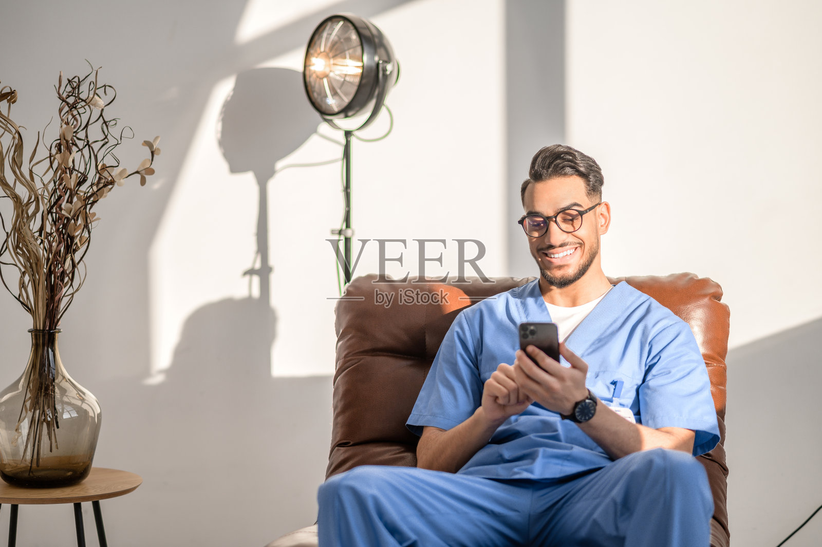 快乐的医生戴着眼镜在扶手椅上休息照片摄影图片