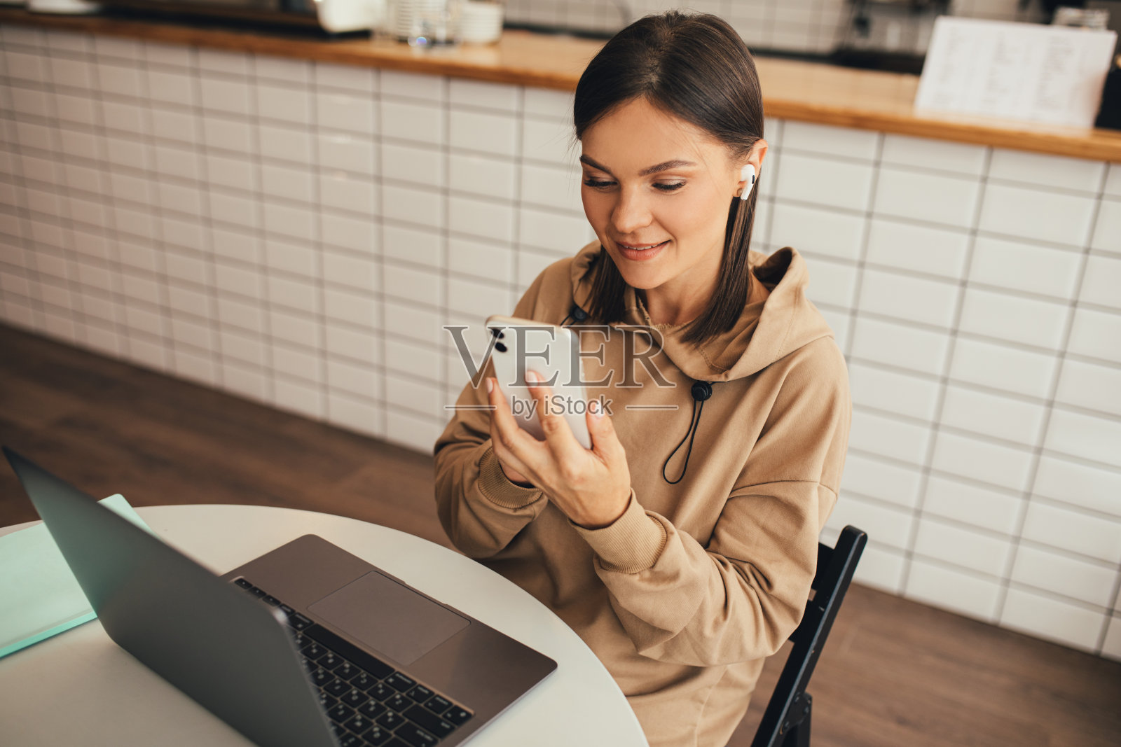 年轻的自由职业者,在一个舒适的咖啡馆里,用笔记本电脑和智能手机在网上工作,喝着咖啡。照片摄影图片