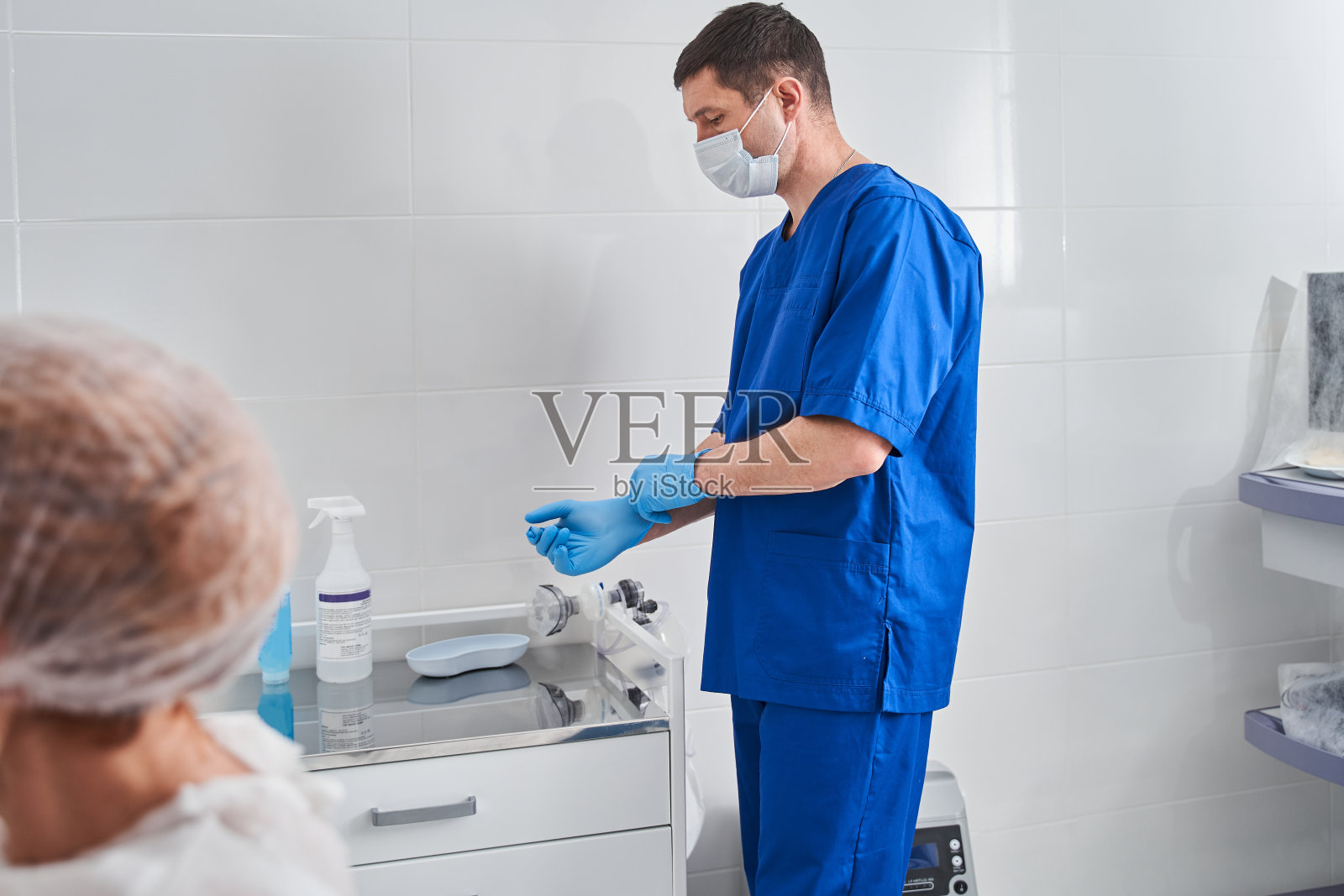 认真的白人医生,戴着防护手套,在诊所准备手术照片摄影图片