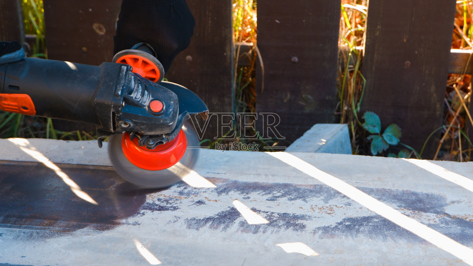 建筑工人用角磨机工作。钢丝清洁刷。清除金属内嵌的锈迹和混凝土。照片摄影图片