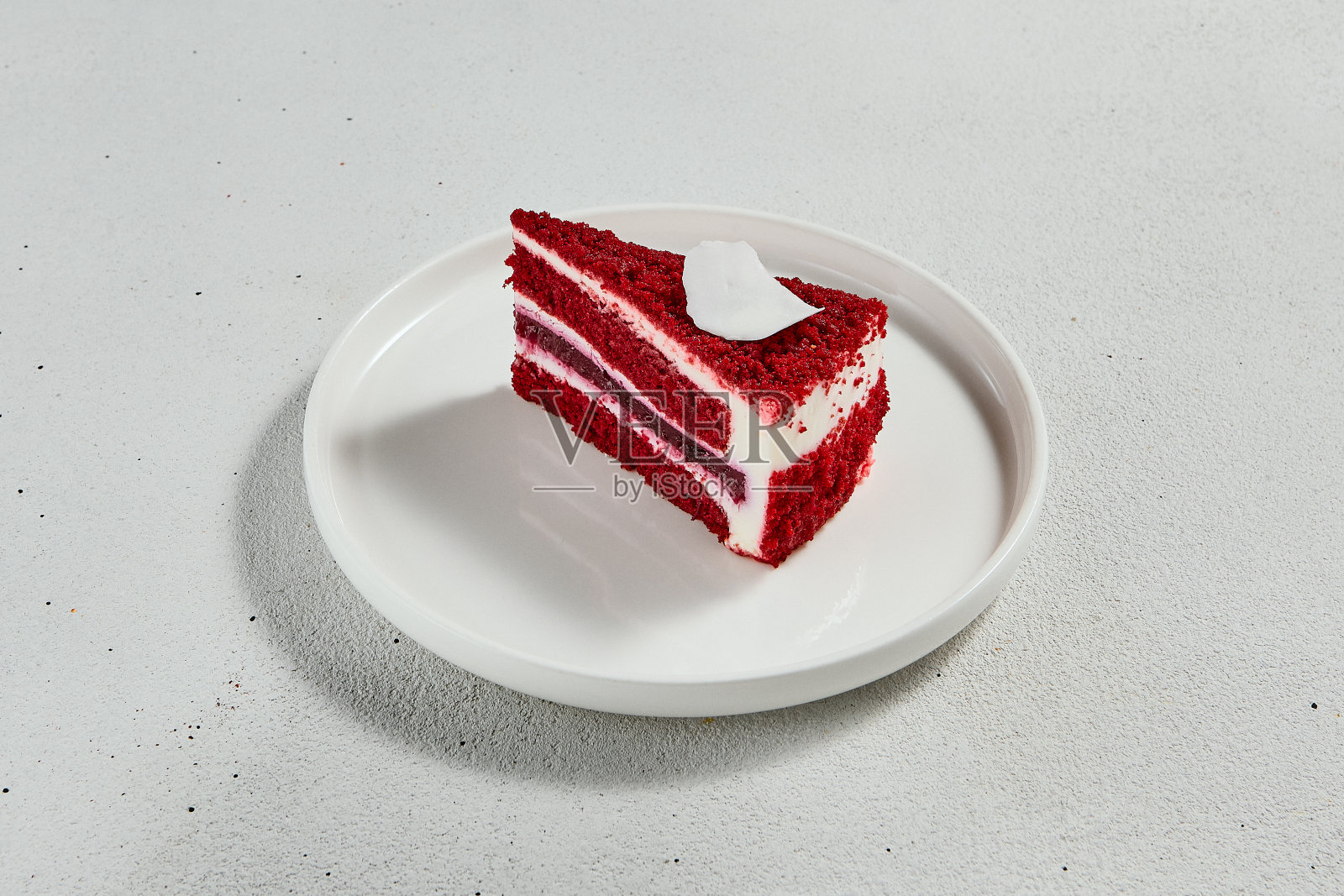 红色丝绒蛋糕放在白色陶瓷盘子上。最小的组合与一块蛋糕。最受欢迎的甜点-红丝绒配芝士奶油和巧克力海绵。简约风格的红色天鹅绒。照片摄影图片