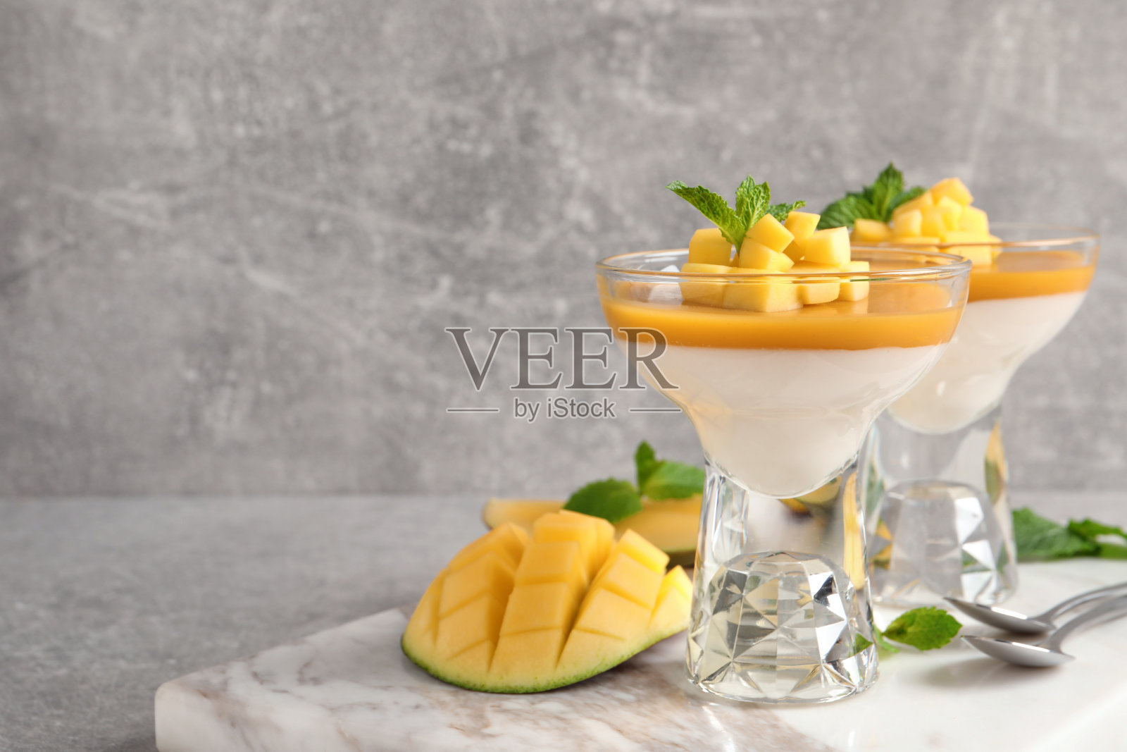 美味的意式奶冻配芒果酱放在浅灰色的桌子上。空间的文本照片摄影图片